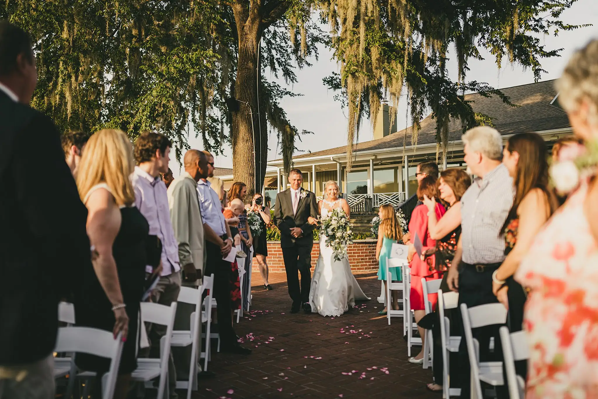 Processional: the bride on her father's arm down the brick aisle, at their wedding at Houston Lake Country Club in Perry, GA