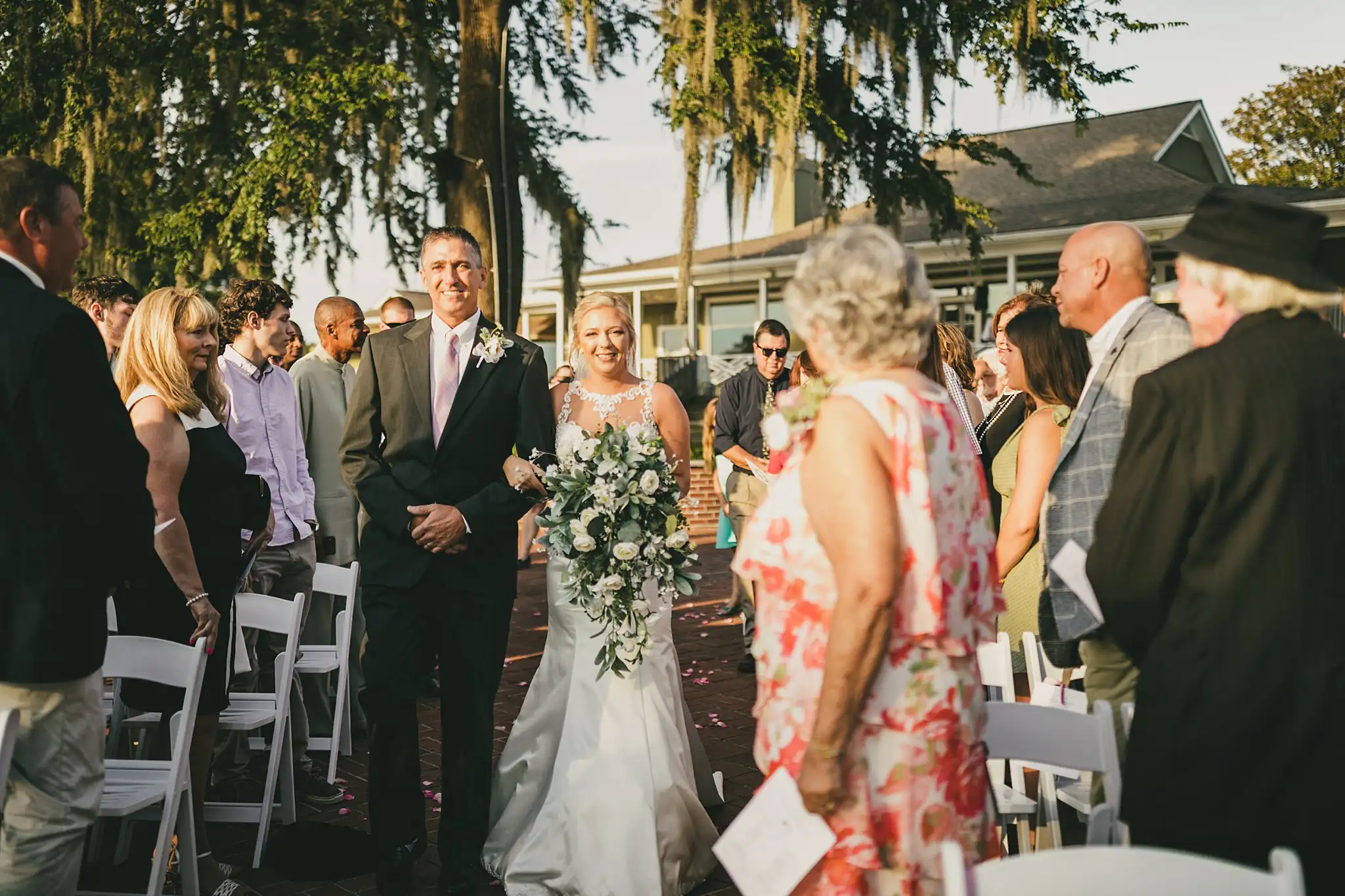Processional: the bride walking in as the guests turn, at their wedding at Houston Lake Country Club in Perry, GA