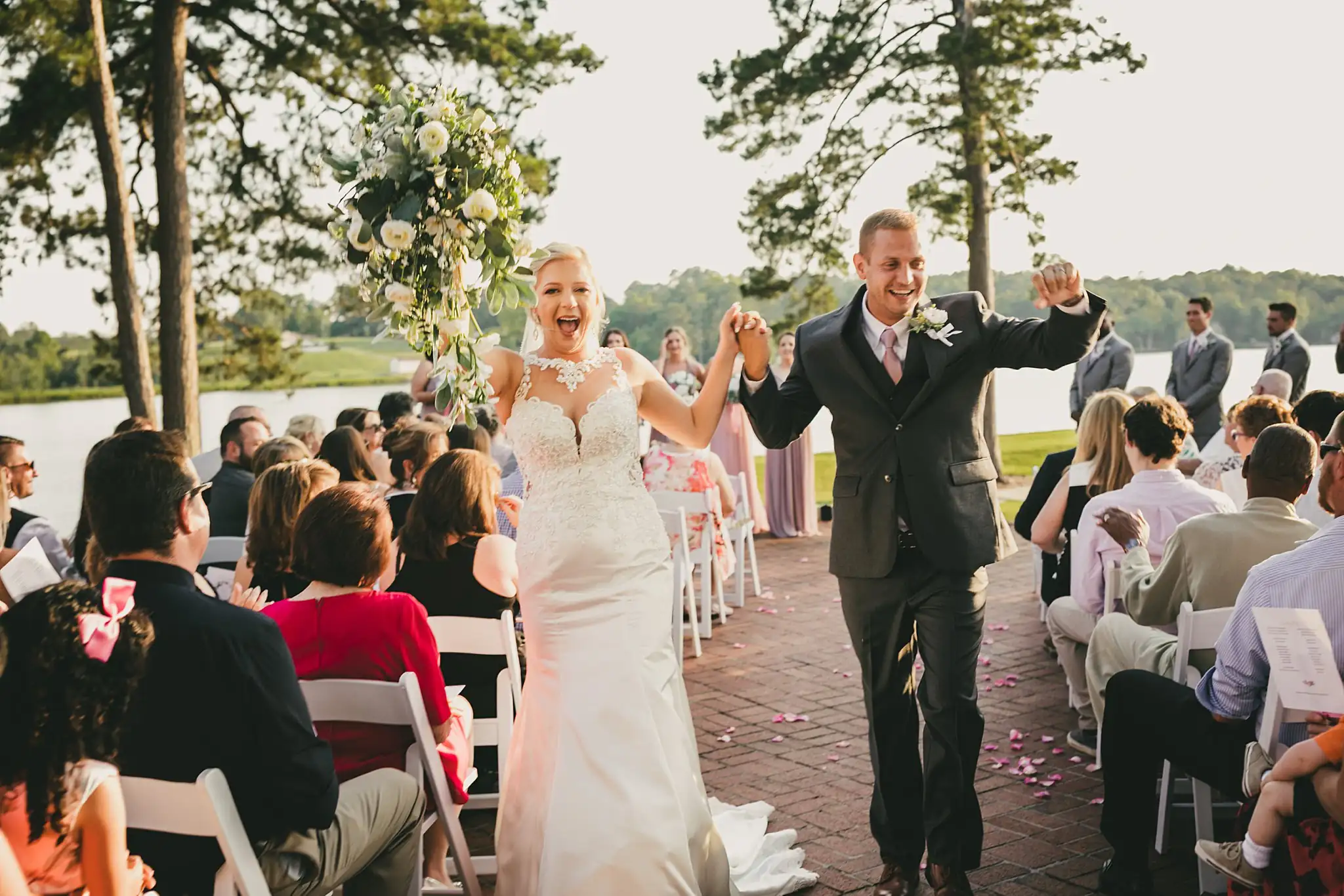 Recessional: the couple coming back up the aisle, arms raised, at their wedding at Houston Lake Country Club in Perry, GA