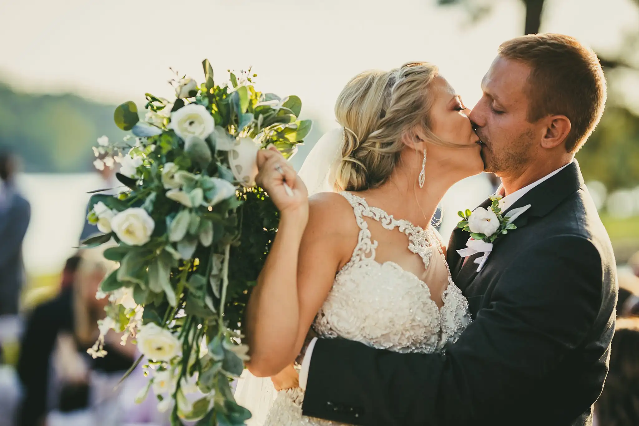 Wedding Formals: the couple kissing, her bouquet raised, at their wedding at Houston Lake Country Club in Perry, GA