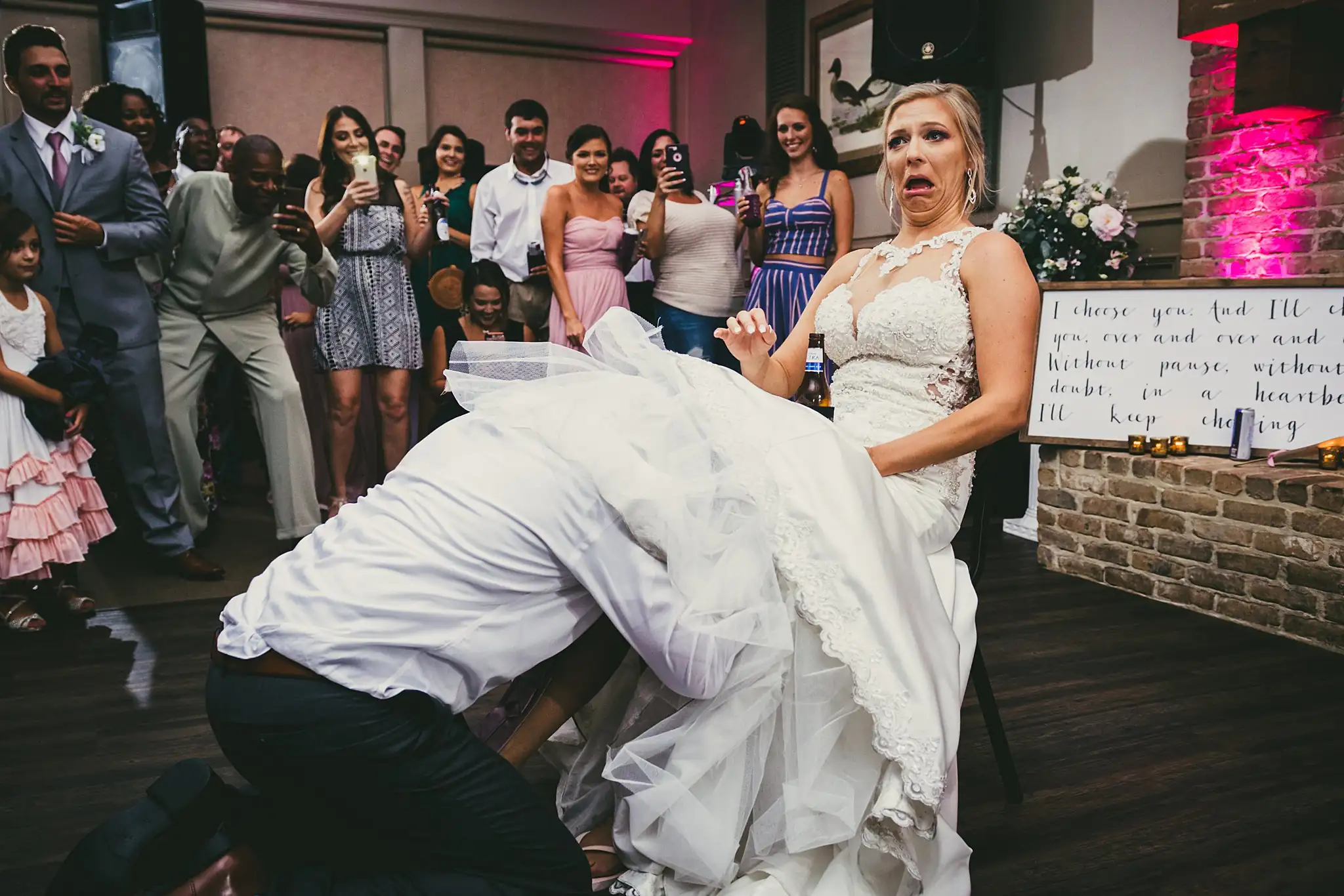 Garter Toss: the garter being taken, the bride laughing, at their wedding at Houston Lake Country Club in Perry, GA