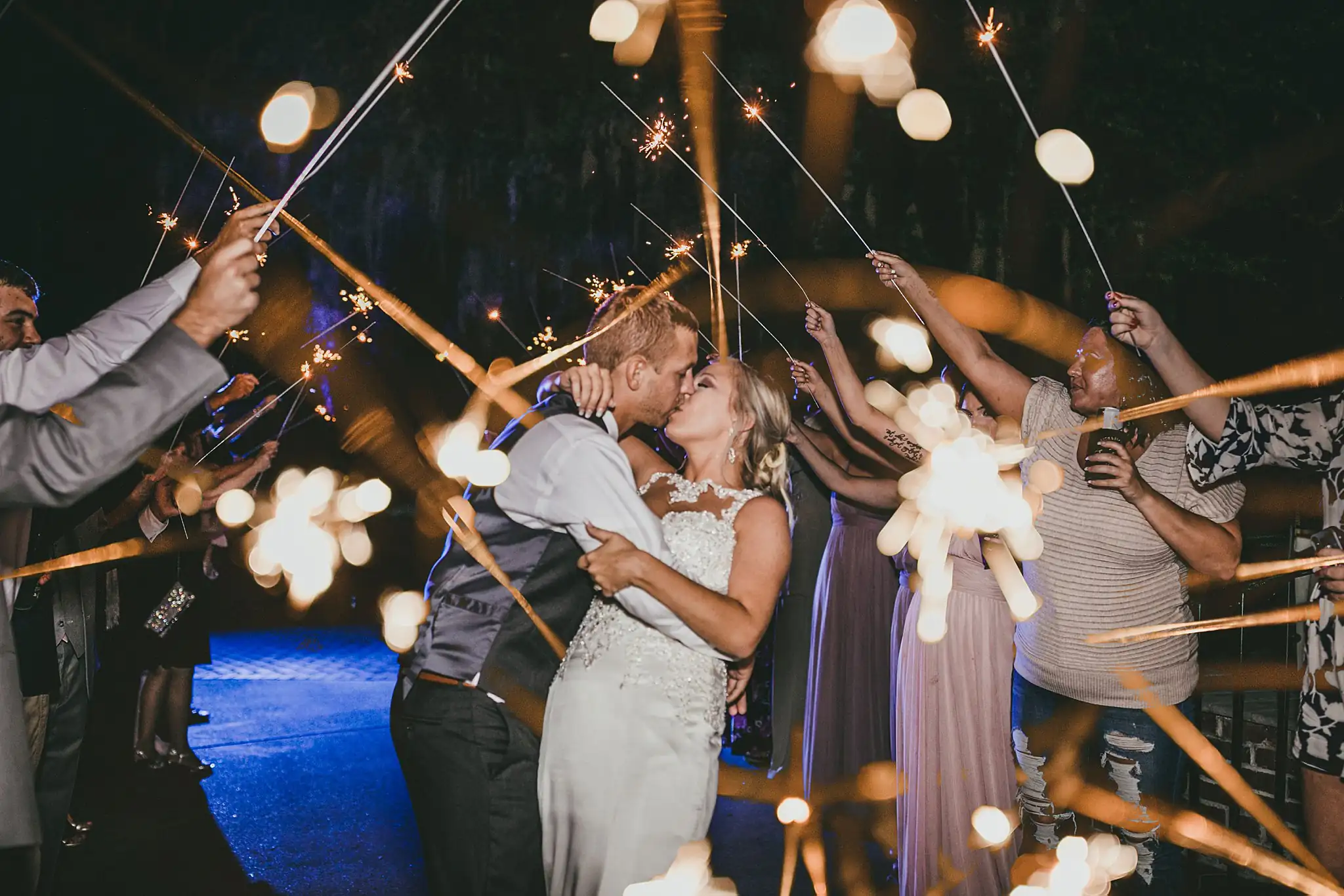 Sparkler Exit: the couple kissing, sparklers all around, at their wedding at Houston Lake Country Club in Perry, GA
