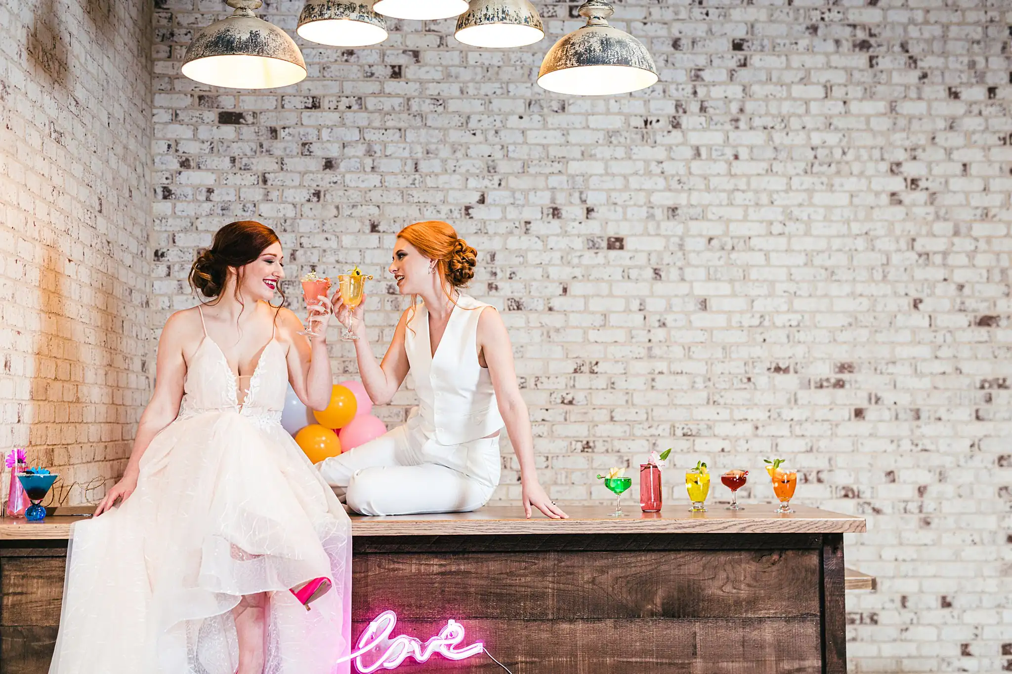 AtlantaWeddingPhotographers_1246.jpg Wedding Reception: the couple on the bar above a neon sign, at a Whimsically in Love LGBTQ Wedding styled shoot at Brick and Ivey in Marietta, GA