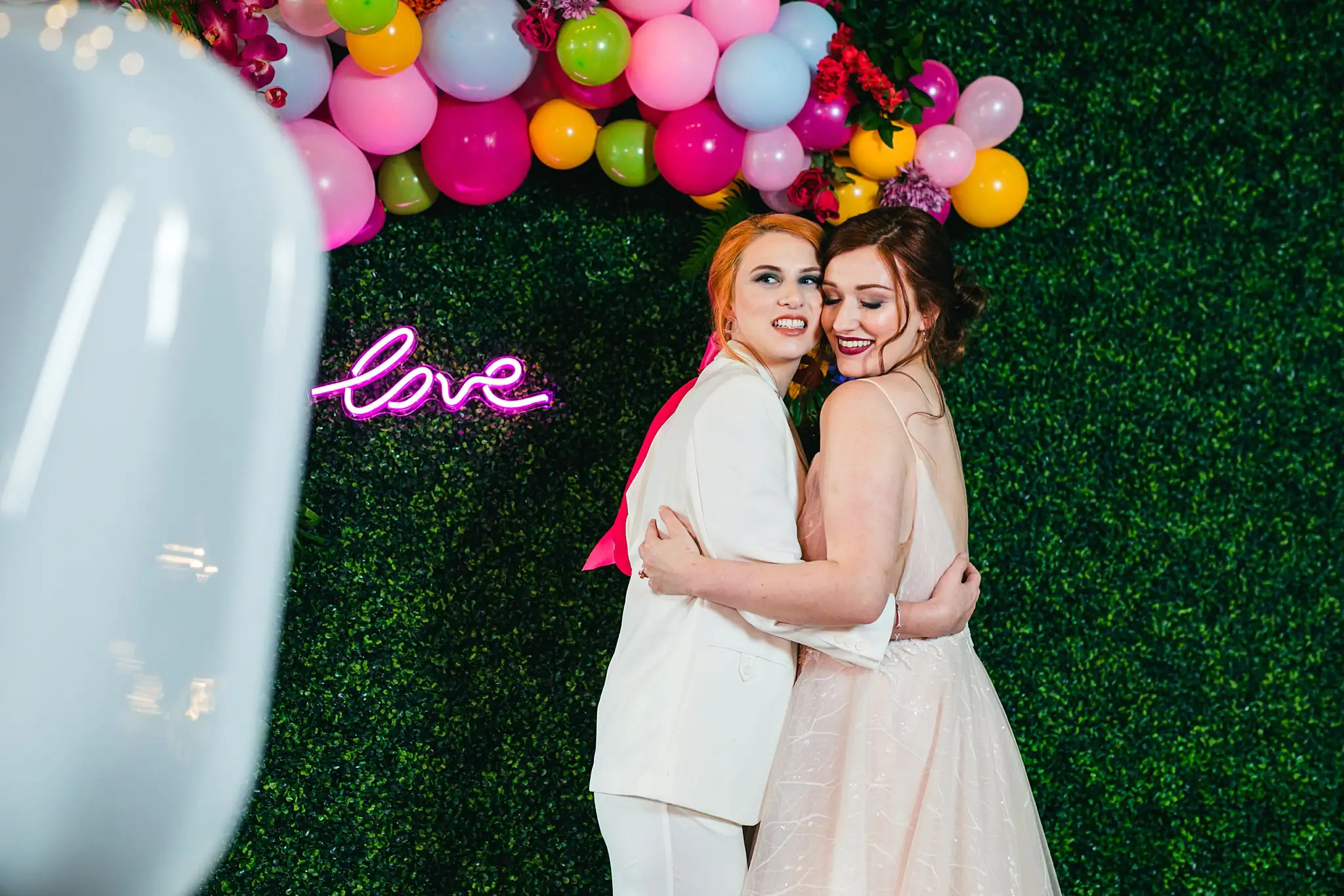 Wedding Formals: the couple embracing by the neon sign, at a Whimsically in Love LGBTQ Wedding styled shoot at Brick and Ivey in Marietta, GA