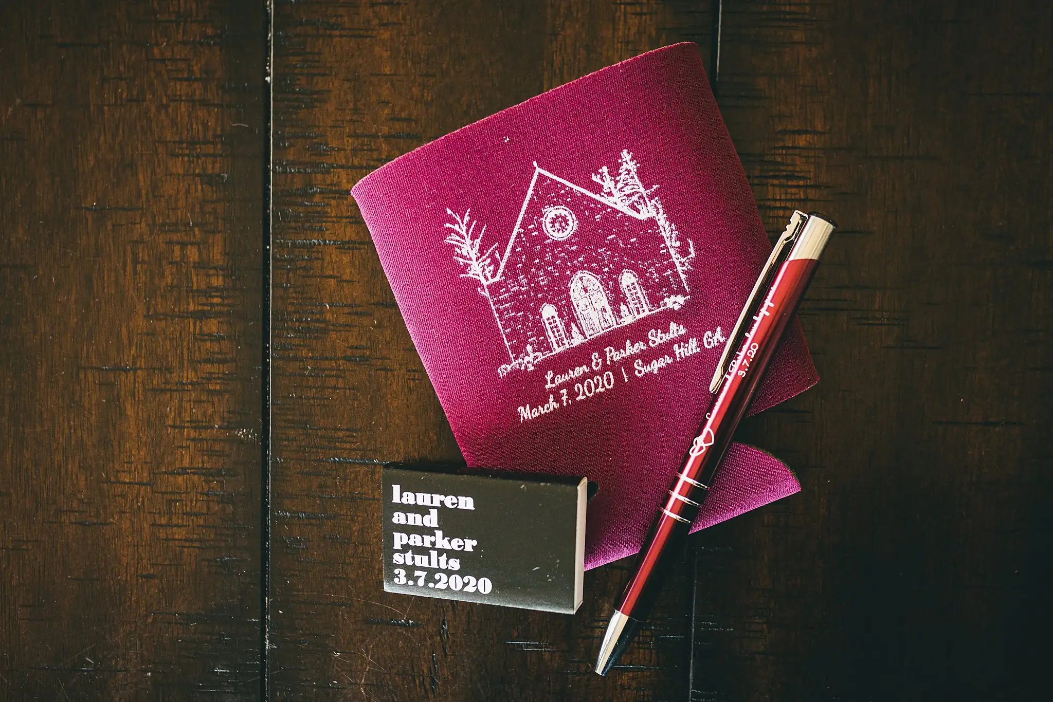Wedding Details: a burgundy koozie and matchbox printed for the day, at a wedding at Ashton Gardens Atlanta in Sugar Hill, GA