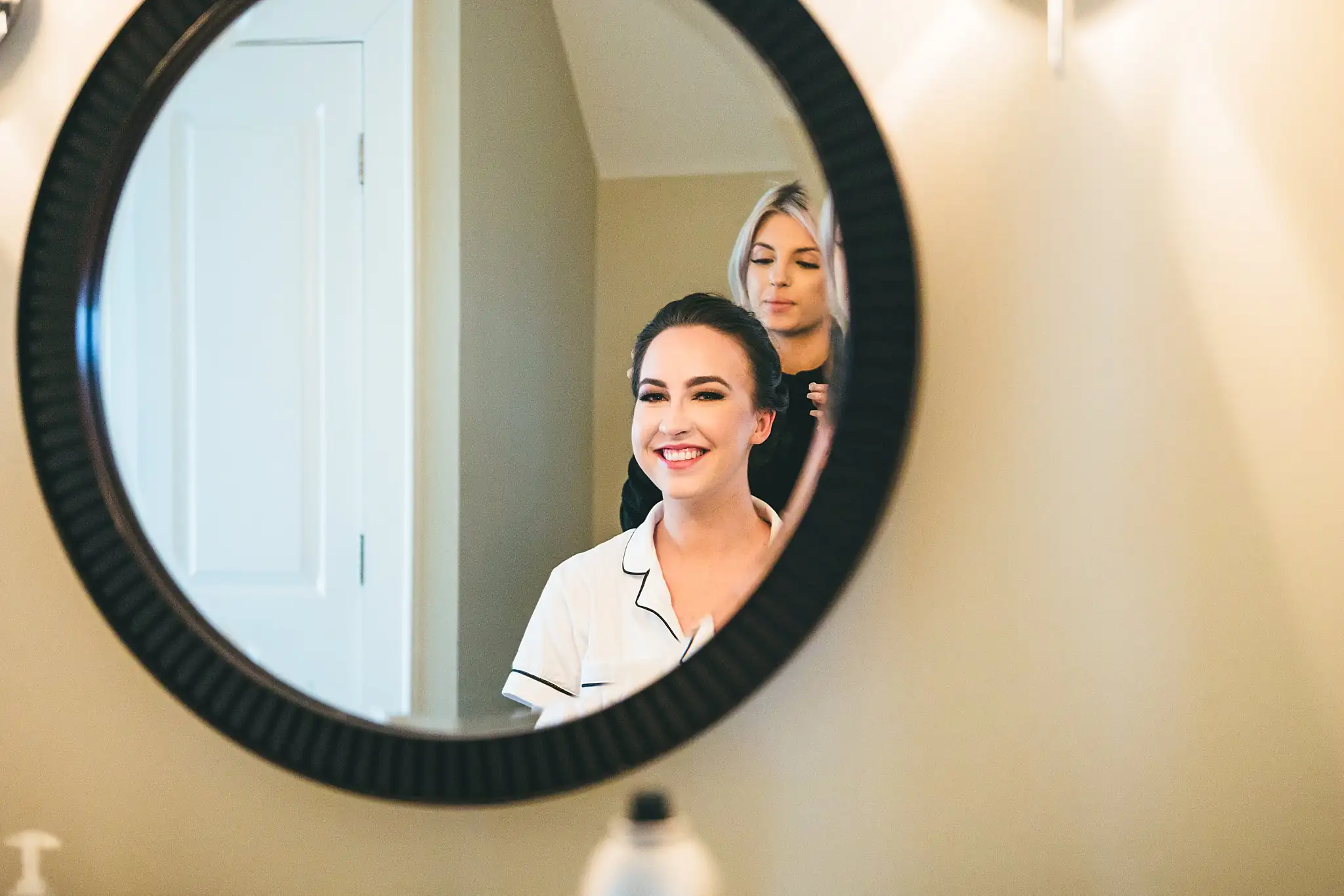 Getting Ready: the bride reflected in a round mirror as her hair is done, before their wedding at Ashton Gardens Atlanta in Sugar Hill, GA