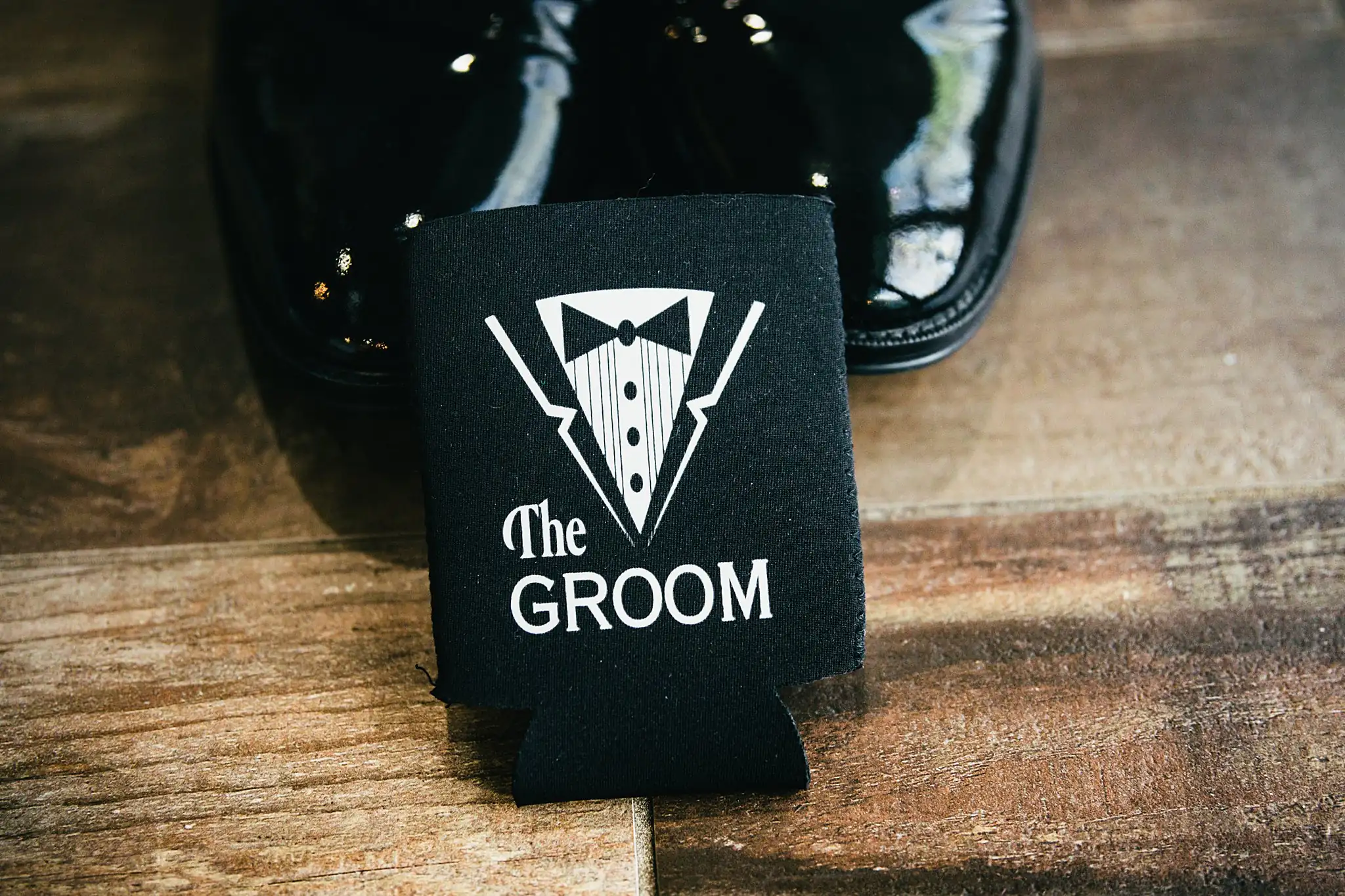 Wedding Details: a koozie lettered The Groom beside his shoes, at a wedding at Ashton Gardens Atlanta in Sugar Hill, GA