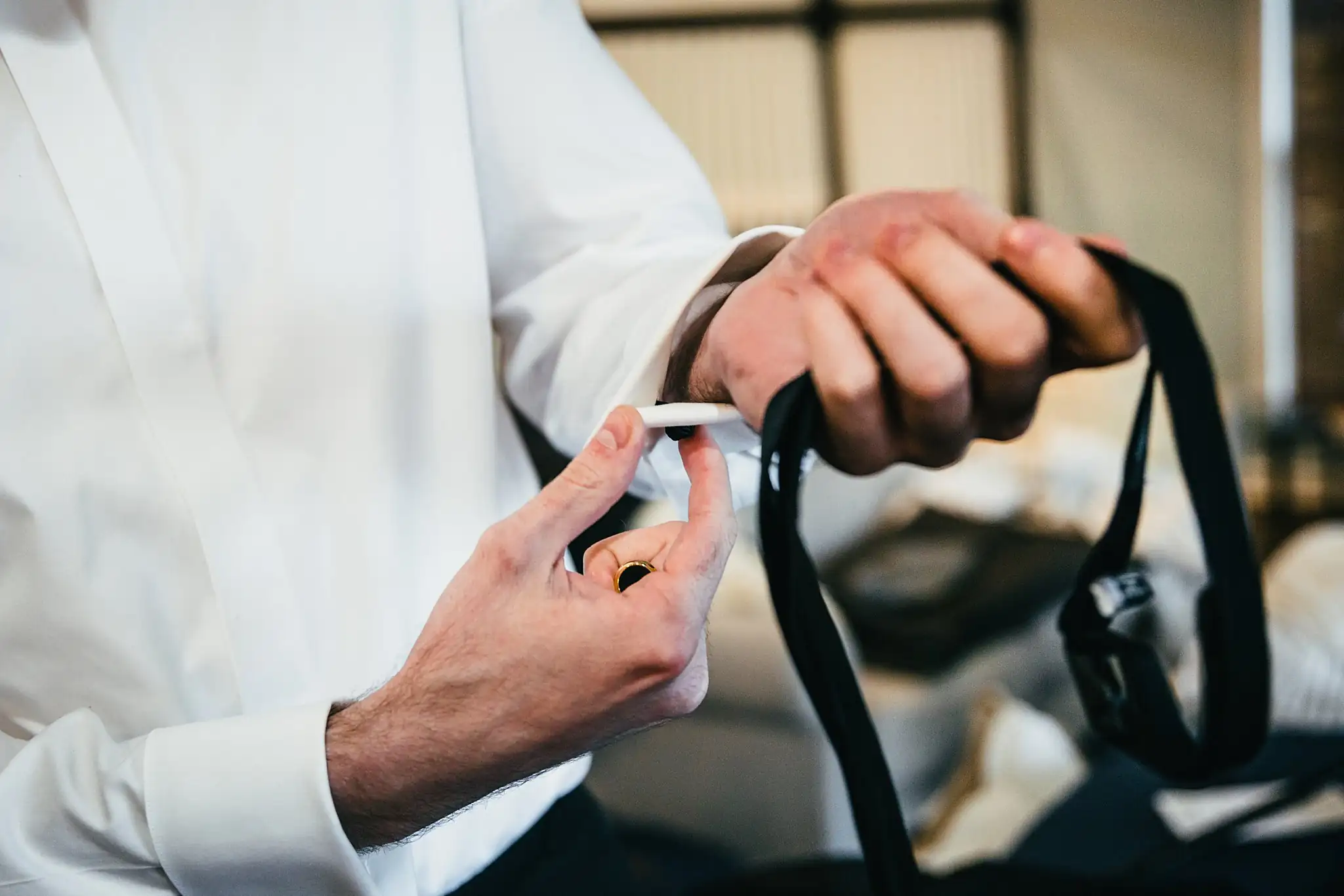 Getting Ready: the groom's hands fastening his bow tie, before their wedding at Ashton Gardens Atlanta in Sugar Hill, GA