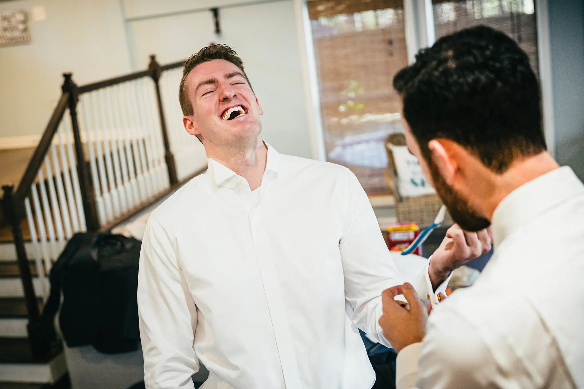 Getting Ready: the groom laughing with a groomsman, before their wedding at Ashton Gardens Atlanta in Sugar Hill, GA