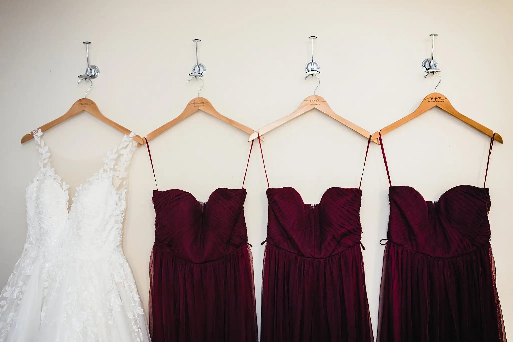 Wedding Details: the gown hanging beside the burgundy bridesmaid dresses, at a wedding at Ashton Gardens Atlanta in Sugar Hill, GA