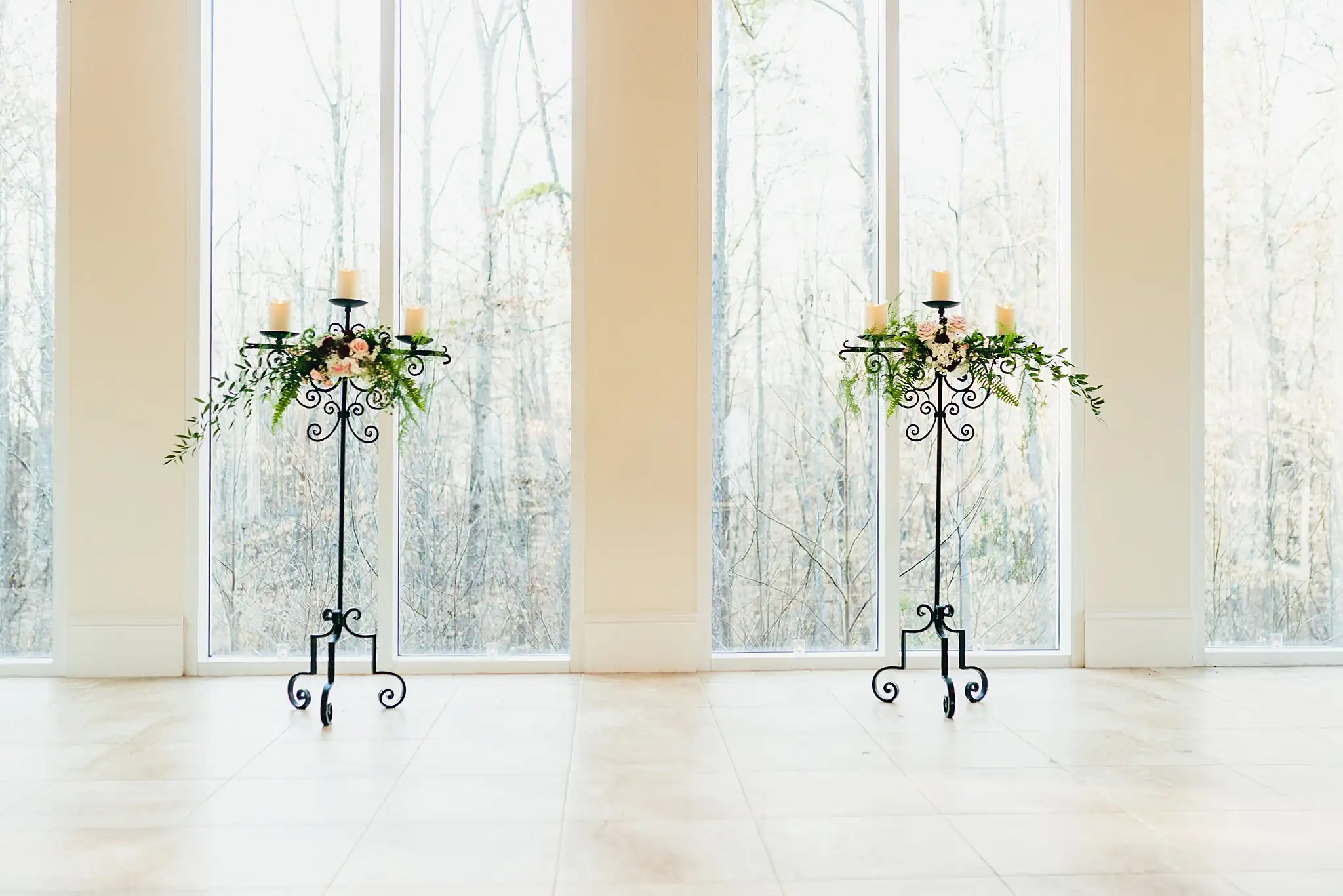 Wedding Florals: candelabra and greenery flanking the glass wall, at a wedding at Ashton Gardens Atlanta in Sugar Hill, GA