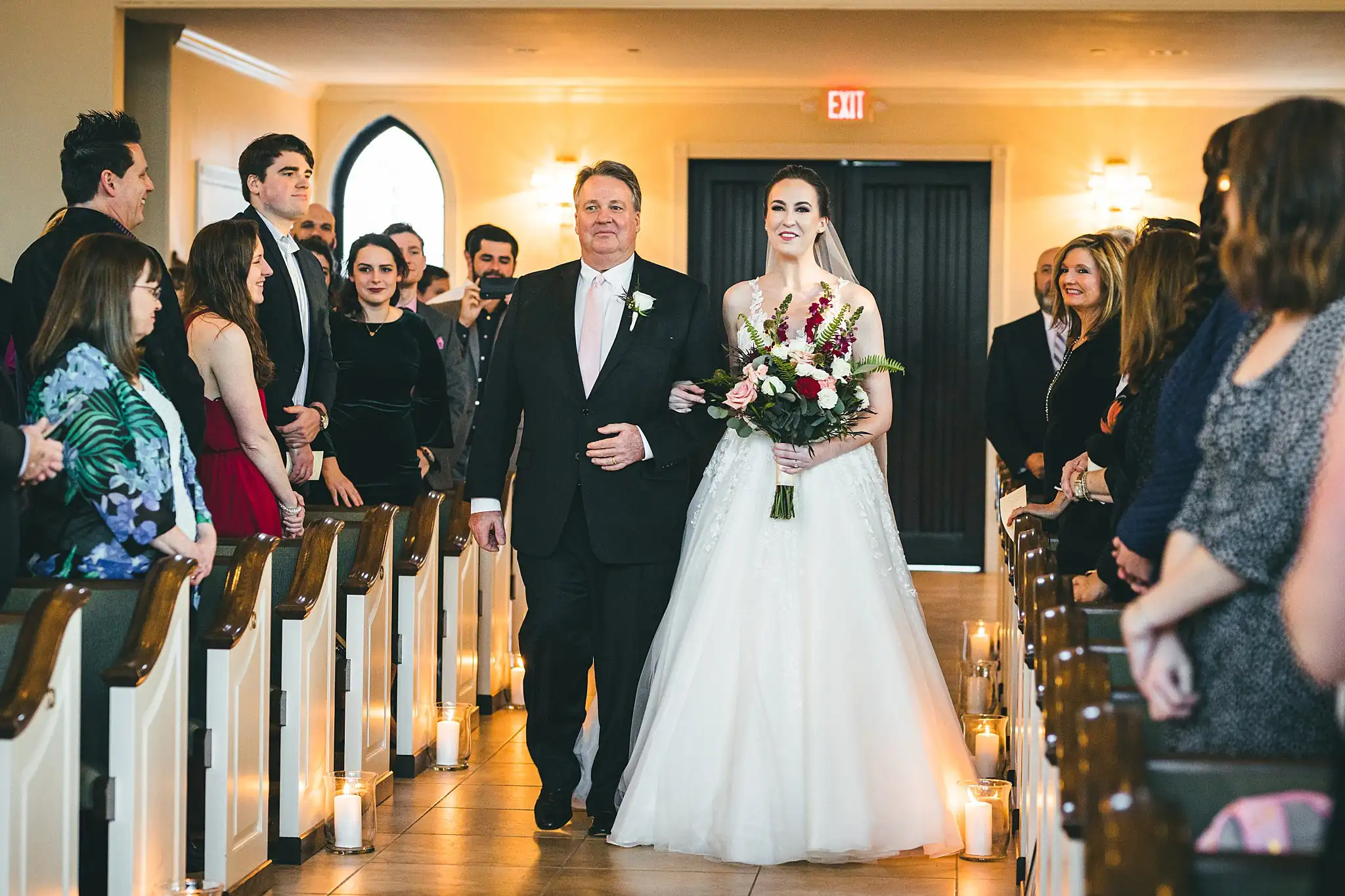 Processional: the bride walking the chapel aisle with her father, at their wedding at Ashton Gardens Atlanta in Sugar Hill, GA