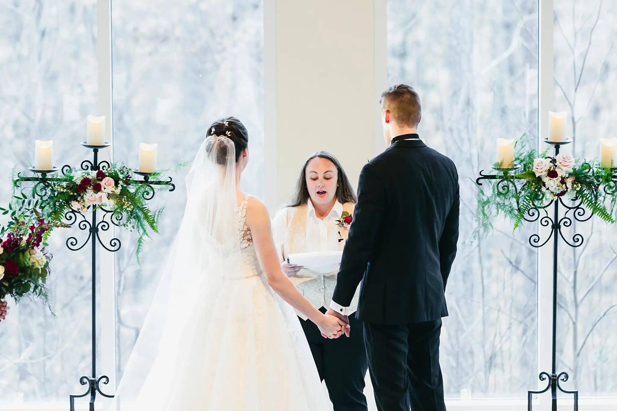 Wedding Ceremony: the couple before the officiant between the candelabra, at their wedding at Ashton Gardens Atlanta in Sugar Hill, GA