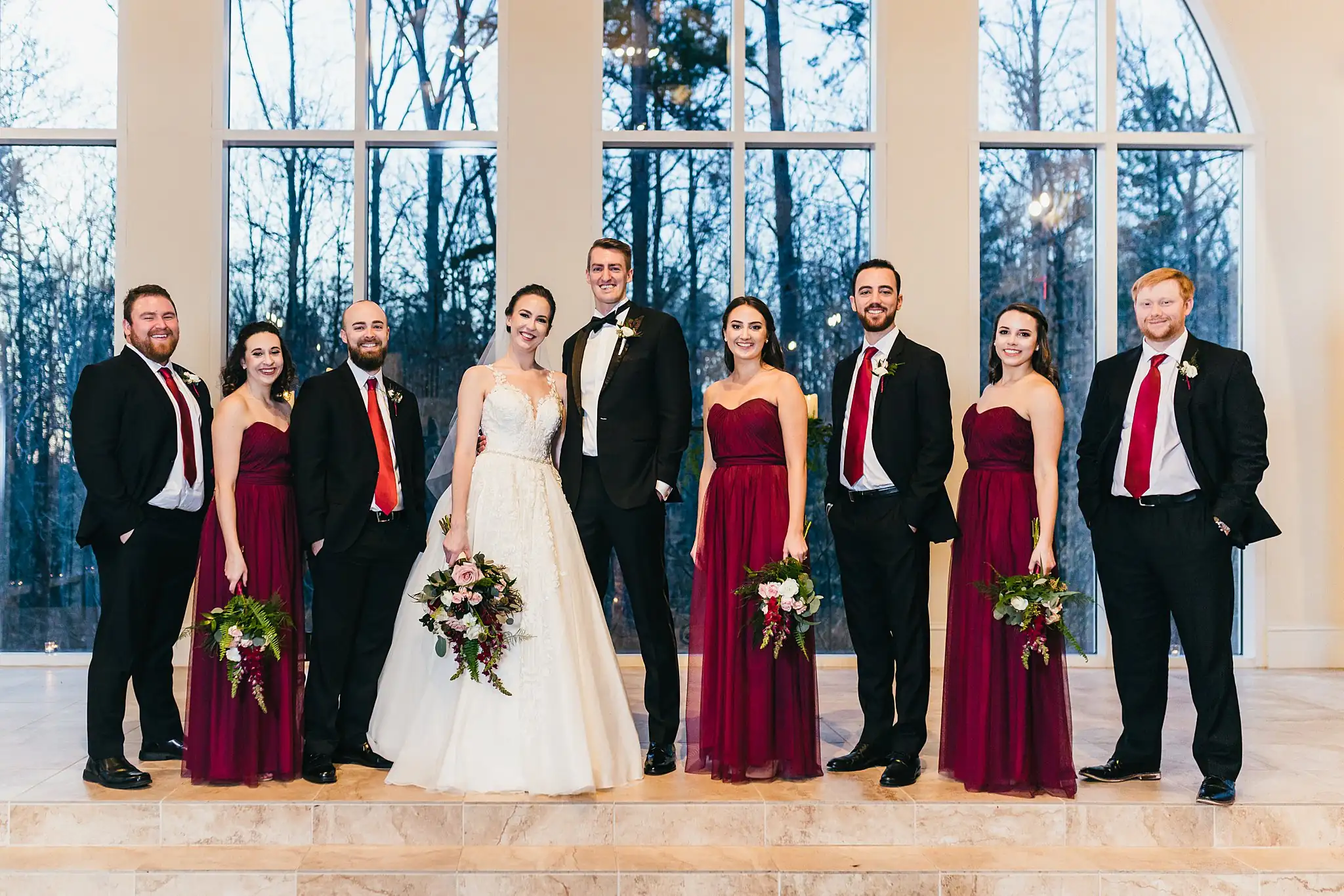 Wedding Party: the bridal party against the chapel's glass wall, at their wedding at Ashton Gardens Atlanta in Sugar Hill, GA