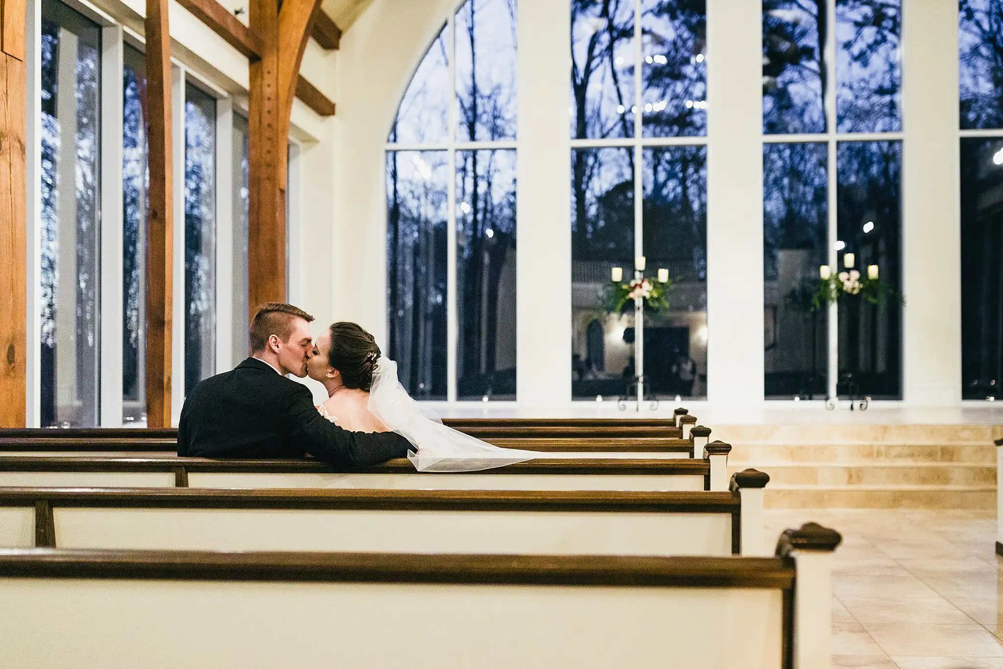 Wedding Formals: the couple kissing in a chapel pew, at their wedding at Ashton Gardens Atlanta in Sugar Hill, GA