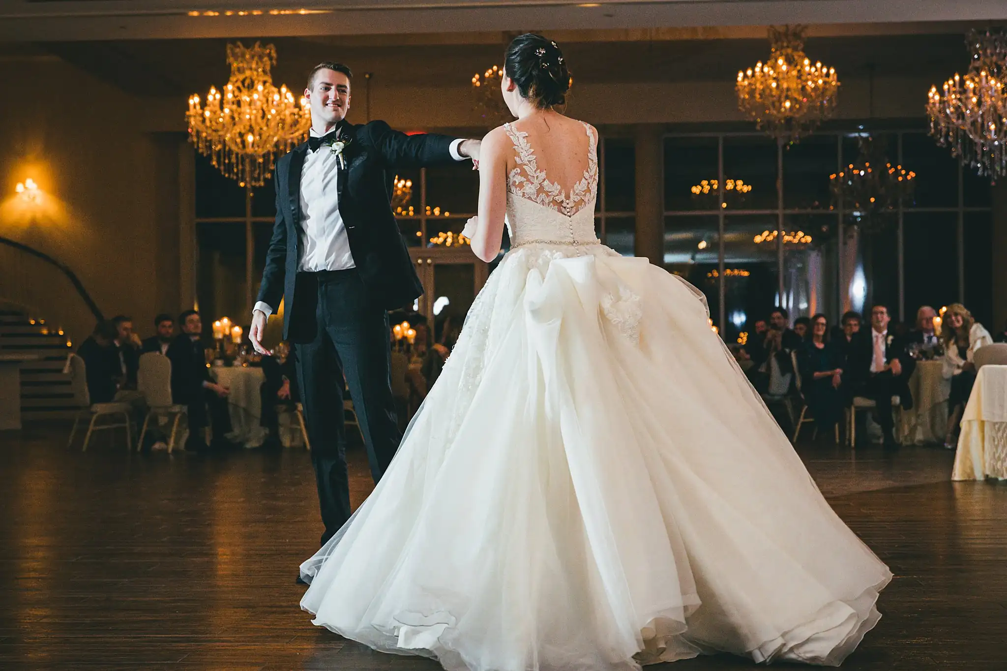 First Dance: the bride's ballgown swirling under the chandeliers, at their wedding at Ashton Gardens Atlanta in Sugar Hill, GA