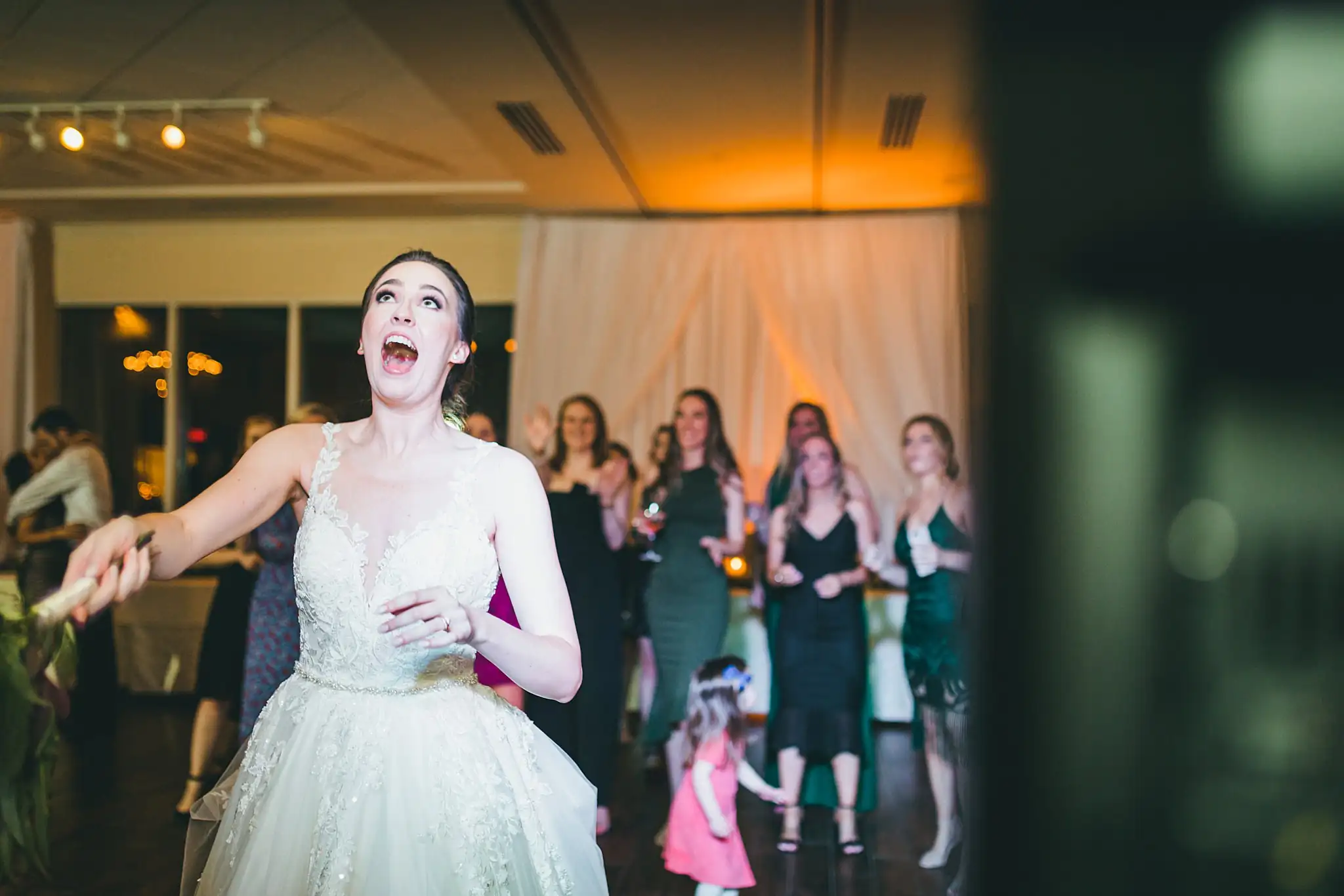 Bouquet Toss: the bouquet thrown, the bride laughing, at their wedding at Ashton Gardens Atlanta in Sugar Hill, GA