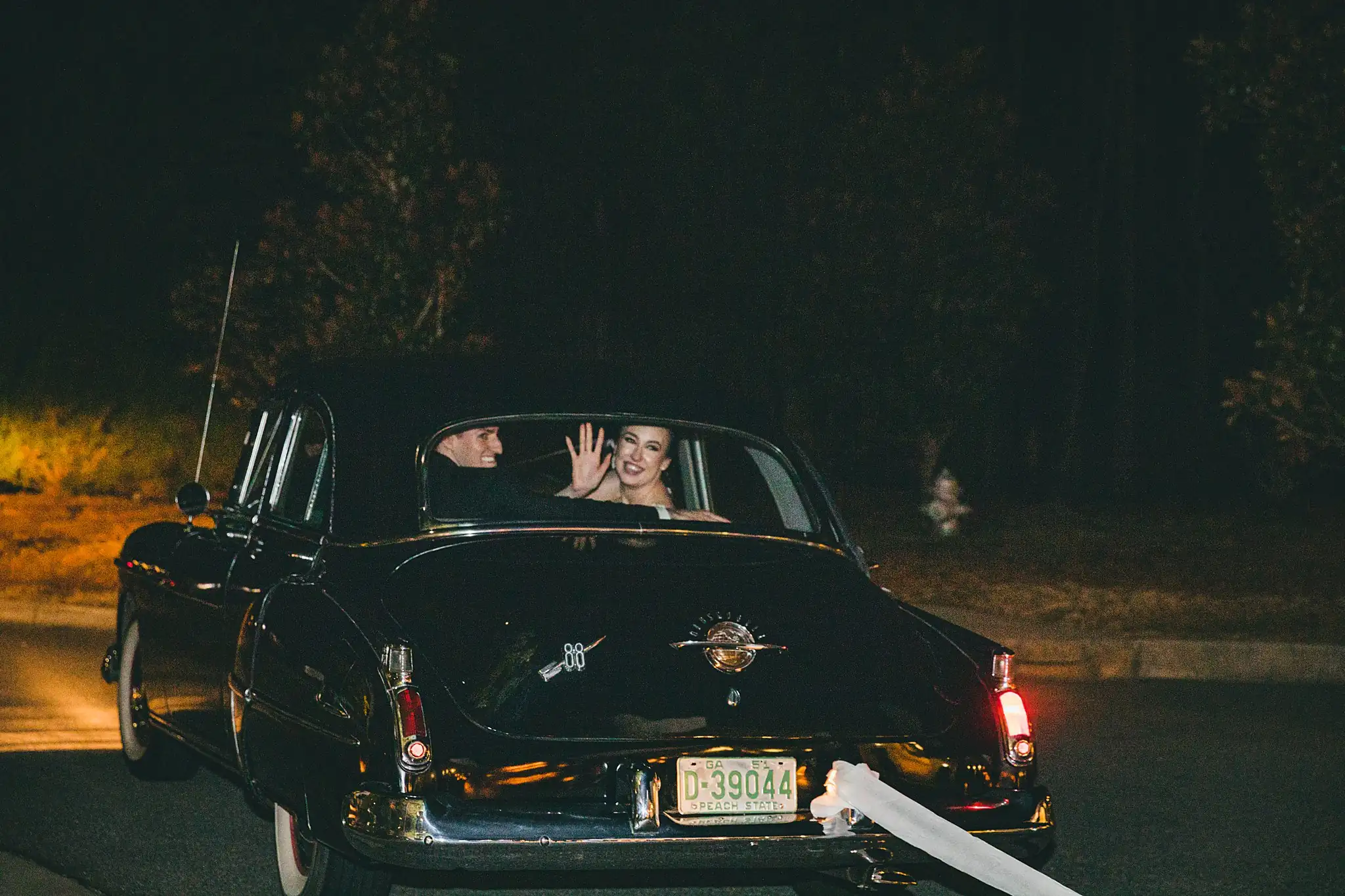 Send-Off: the couple waving as the car drives off, at their wedding at Ashton Gardens Atlanta in Sugar Hill, GA