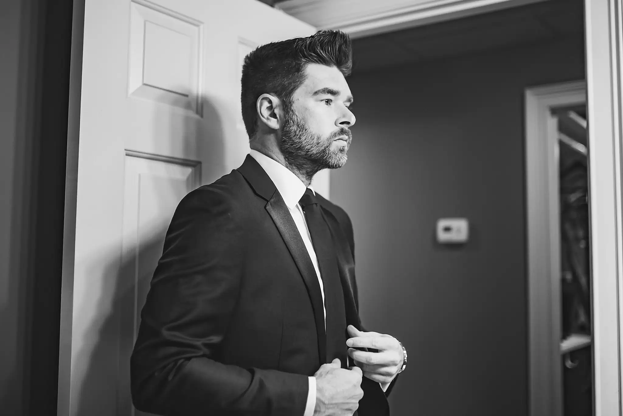 AtlantaWeddingPhotographers_1428.jpg Getting Ready: the groom buttoning his jacket, in black and white, before their wedding at Three Birches in Alpharetta, GA