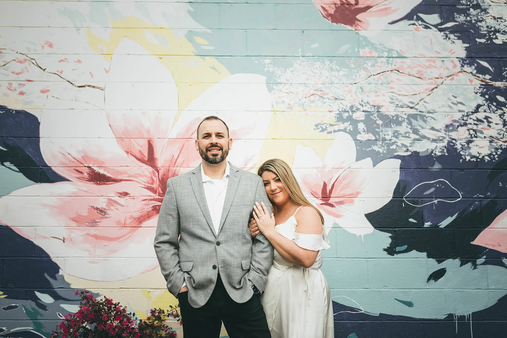 Engagement Portraits: the two of them against the painted magnolia wall, during their engagement session at Marietta Square in Marietta, GA