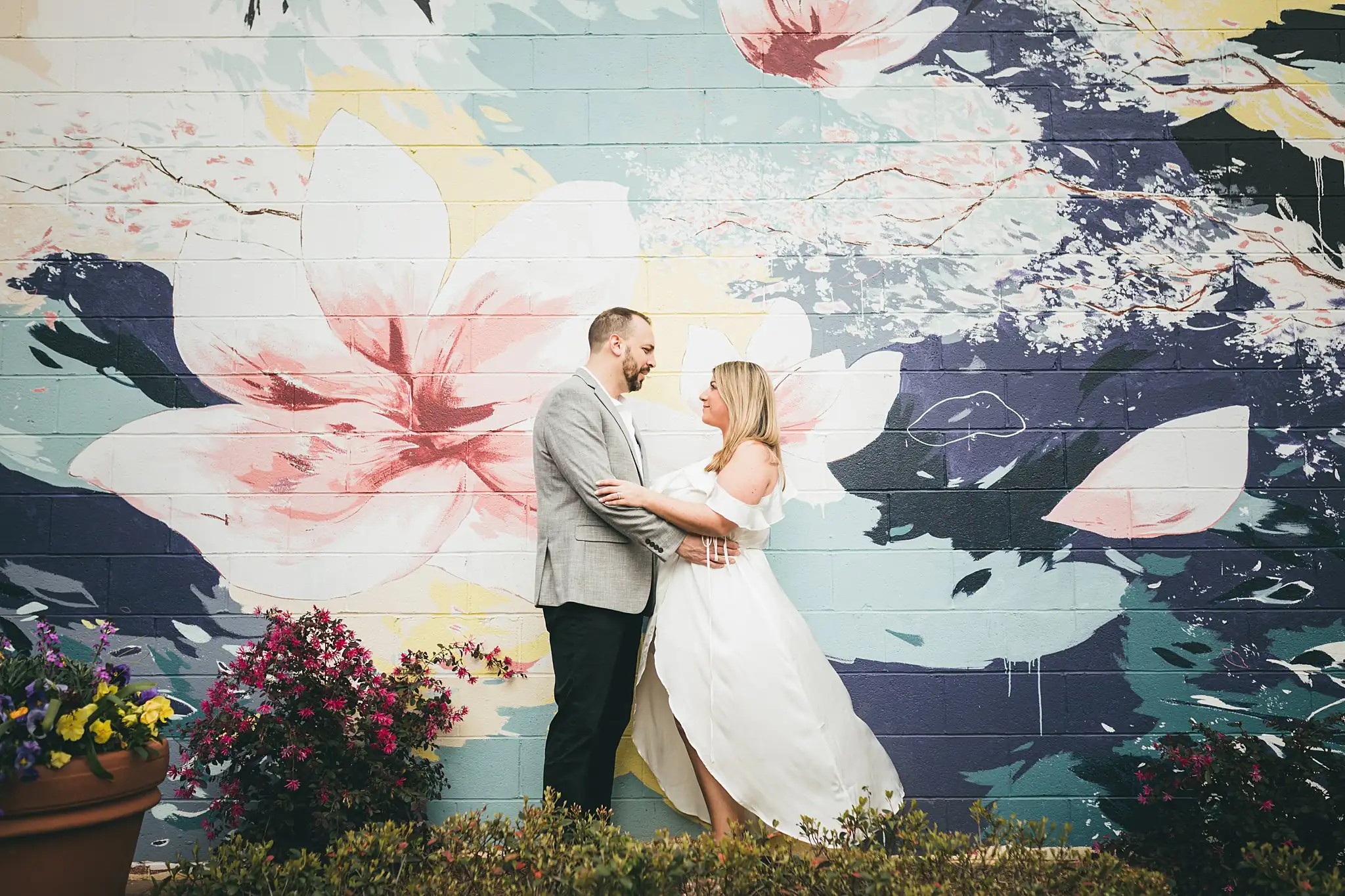 Engagement Portraits: the couple in front of the mural, her skirt out, during their engagement session at Marietta Square in Marietta, GA