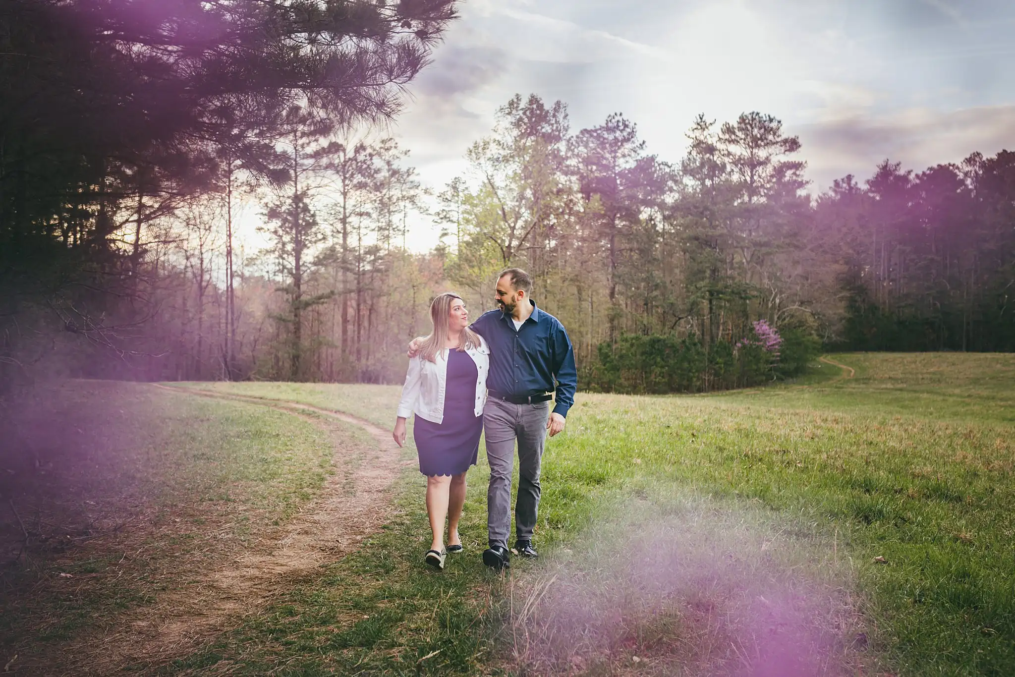 Engagement Portraits: the couple walking the meadow in the late light, during their engagement session at Kennesaw Mountain in Kennesaw, GA