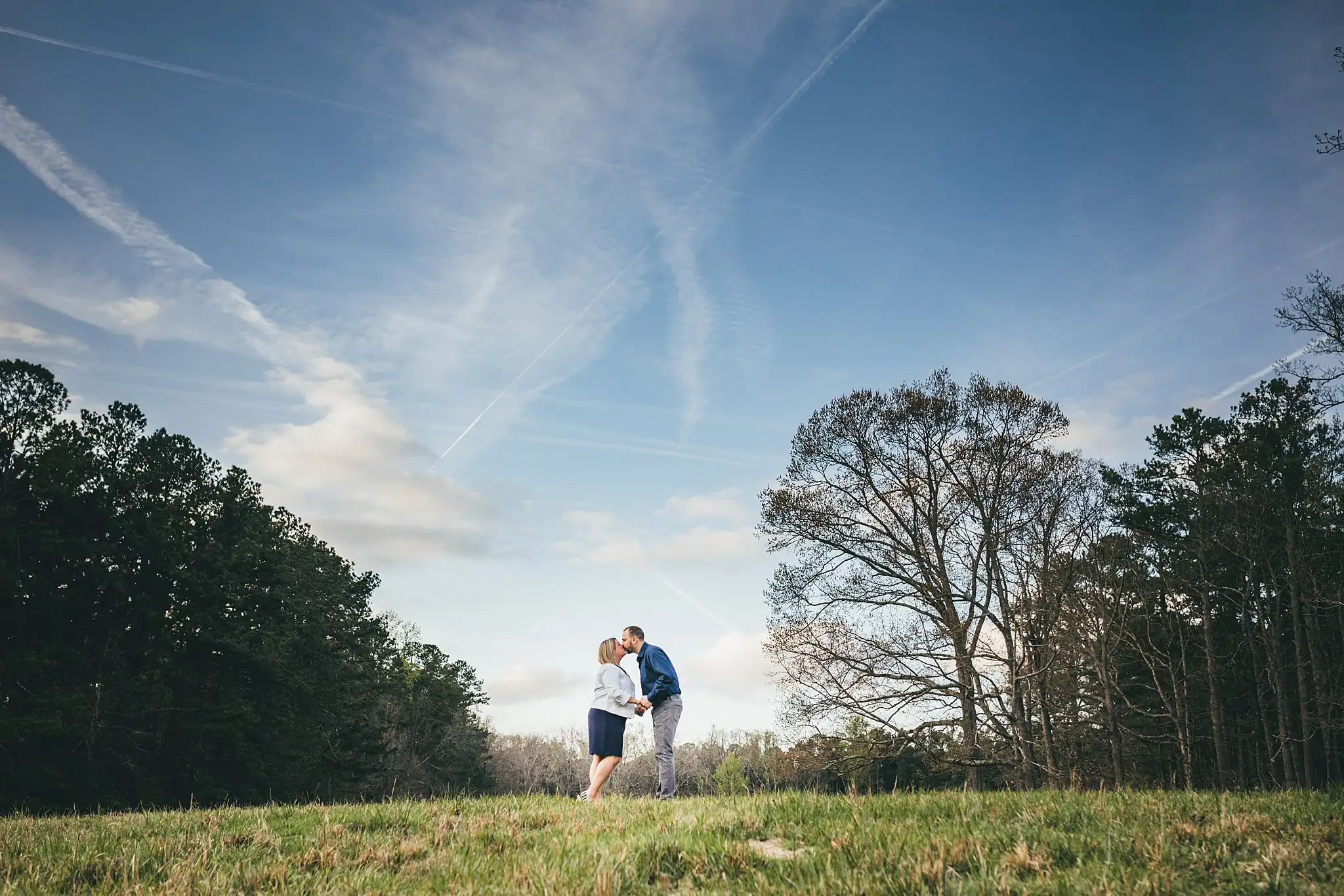 Engagement Portraits: the two of them small under a wide sky, during their engagement session at Kennesaw Mountain in Kennesaw, GA