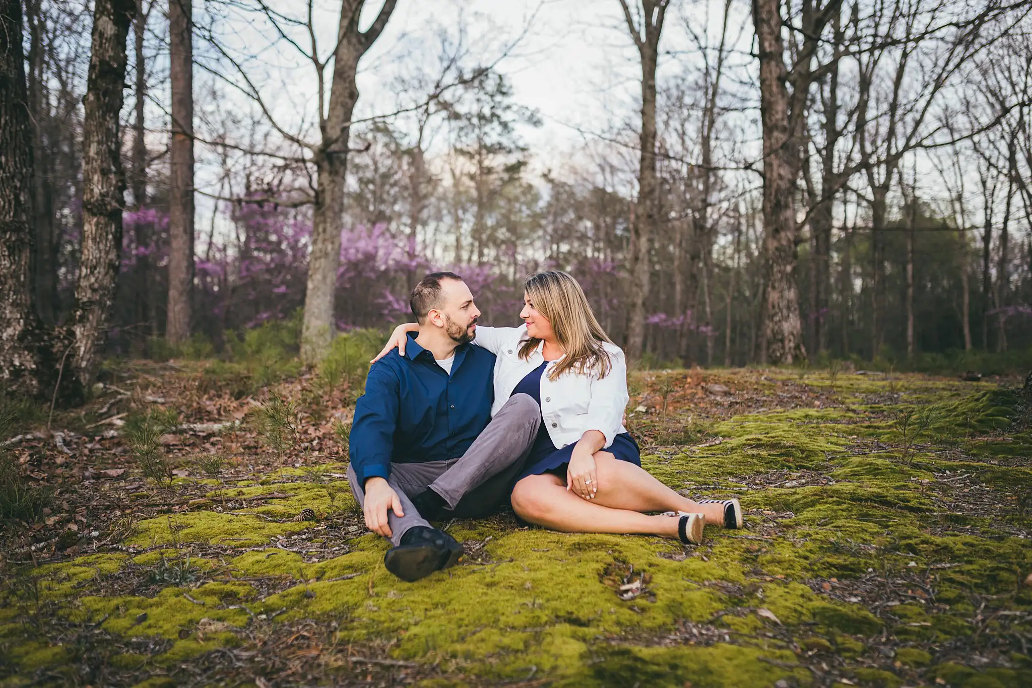 Engagement Portraits: the couple sitting together on the moss, during their engagement session at Kennesaw Mountain in Kennesaw, GA