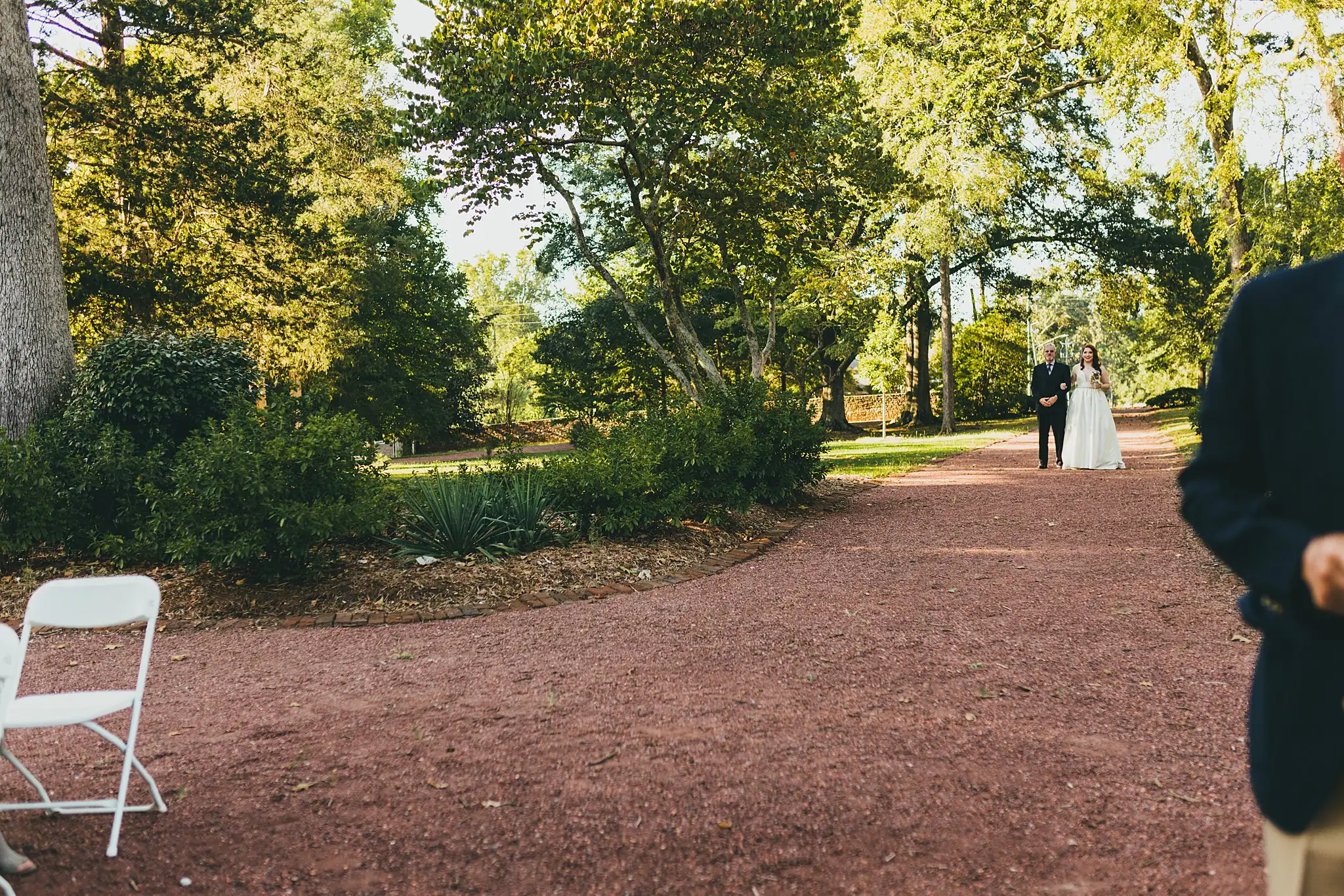 AtlantaWeddingPhotographers_1561.jpg Processional: the bride far off down the shaded path, at their micro ceremony at Barrington Hall in Roswell, GA