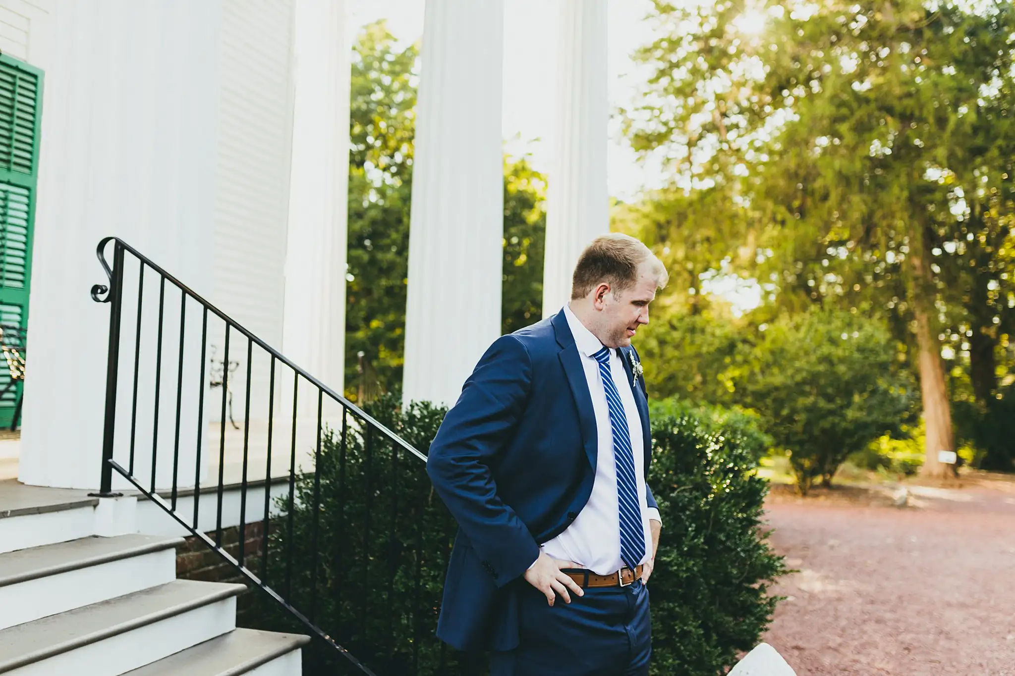 AtlantaWeddingPhotographers_1562.jpg Processional: the groom waiting between the white columns, at their micro ceremony at Barrington Hall in Roswell, GA