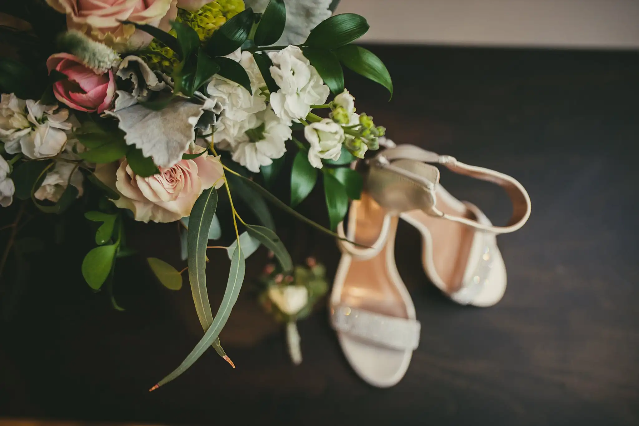 Wedding Details: the bouquet and heels on a dark table, at a wedding at the Atlanta Botanical Garden in Atlanta, GA