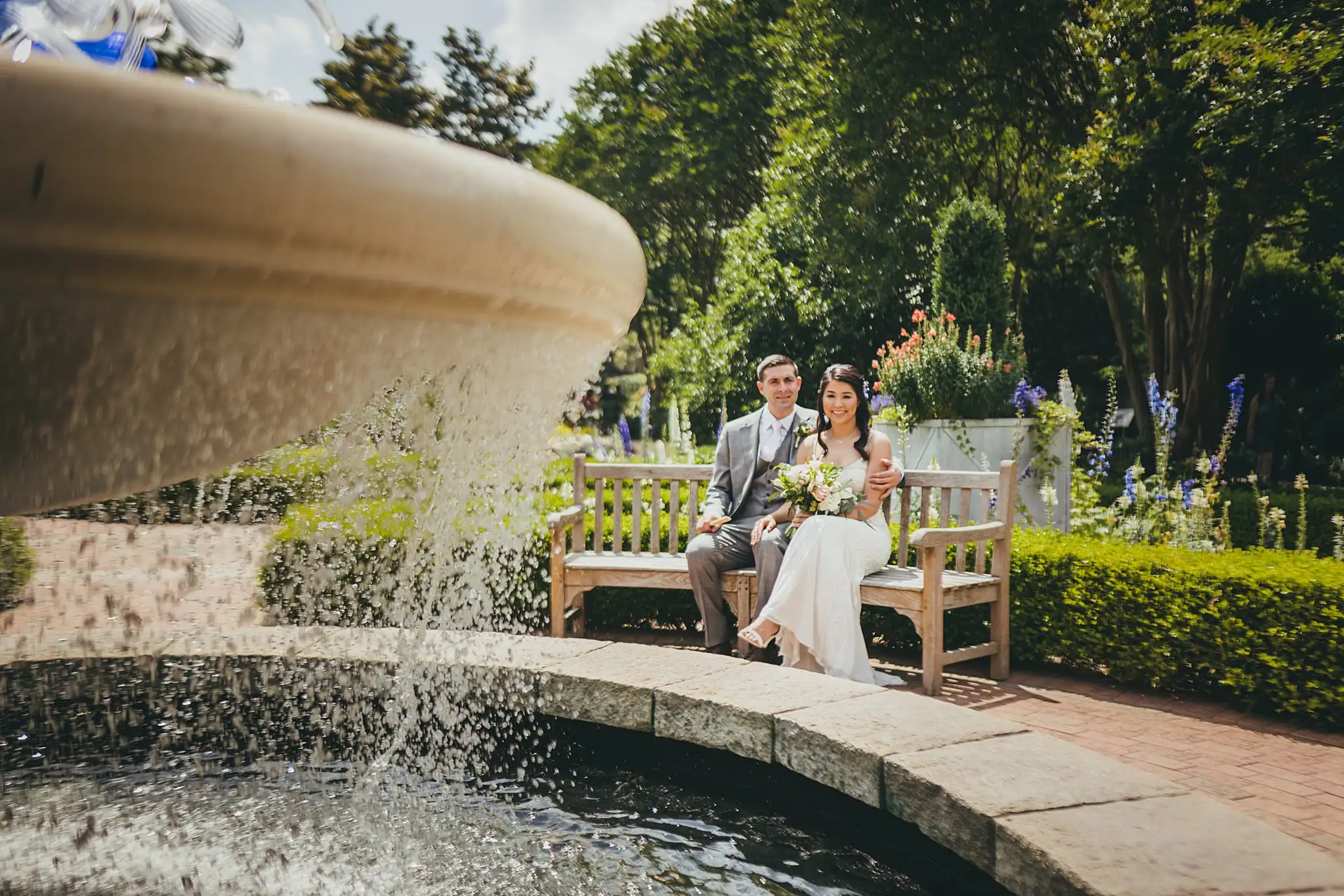 Wedding Formals: the couple on a bench beyond the fountain, at their wedding at the Atlanta Botanical Garden in Atlanta, GA