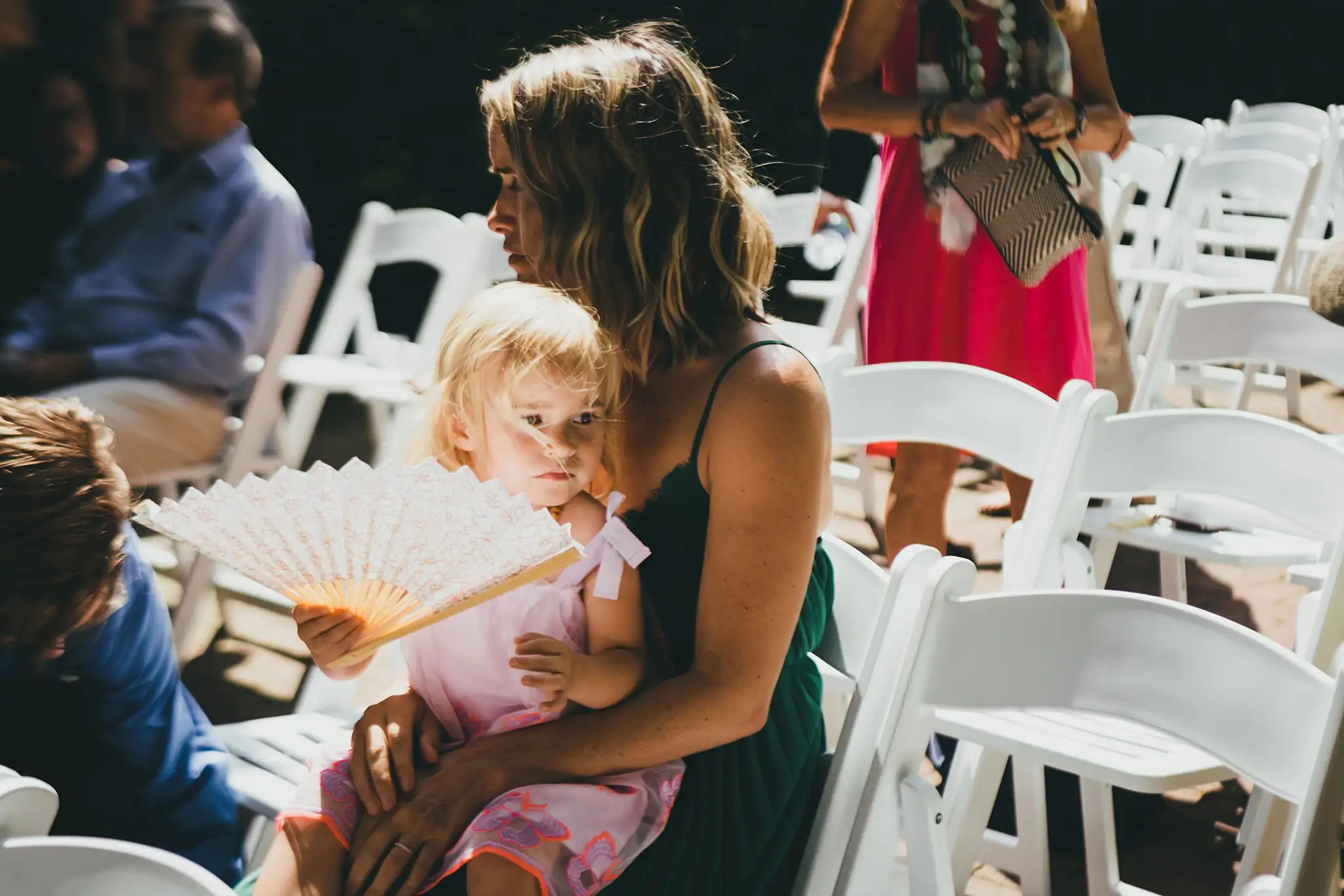 Wedding Ceremony: a guest and a small child with a fan, at their wedding at the Atlanta Botanical Garden in Atlanta, GA
