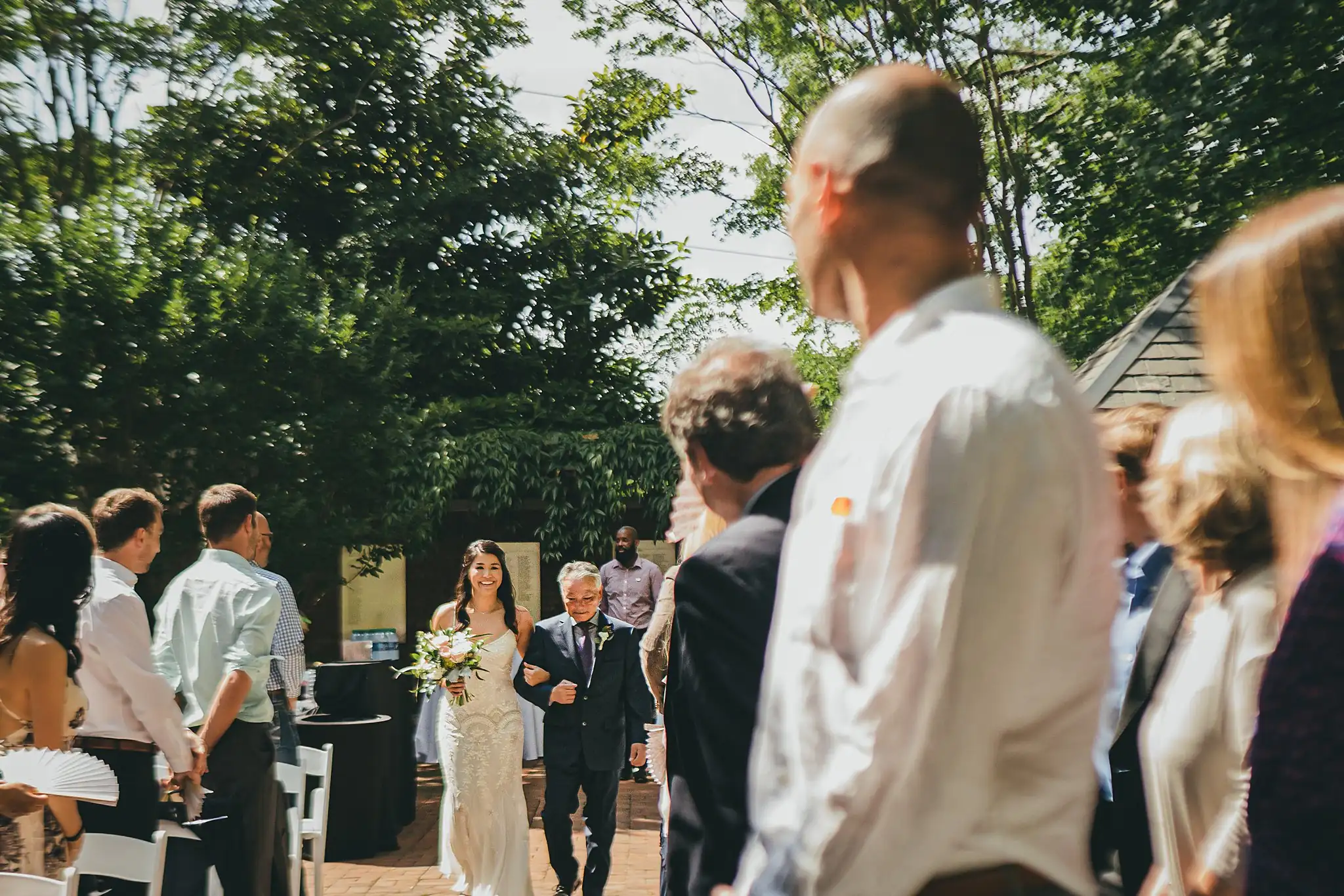 Wedding Ceremony: the guests standing as the ceremony begins, at their wedding at the Atlanta Botanical Garden in Atlanta, GA