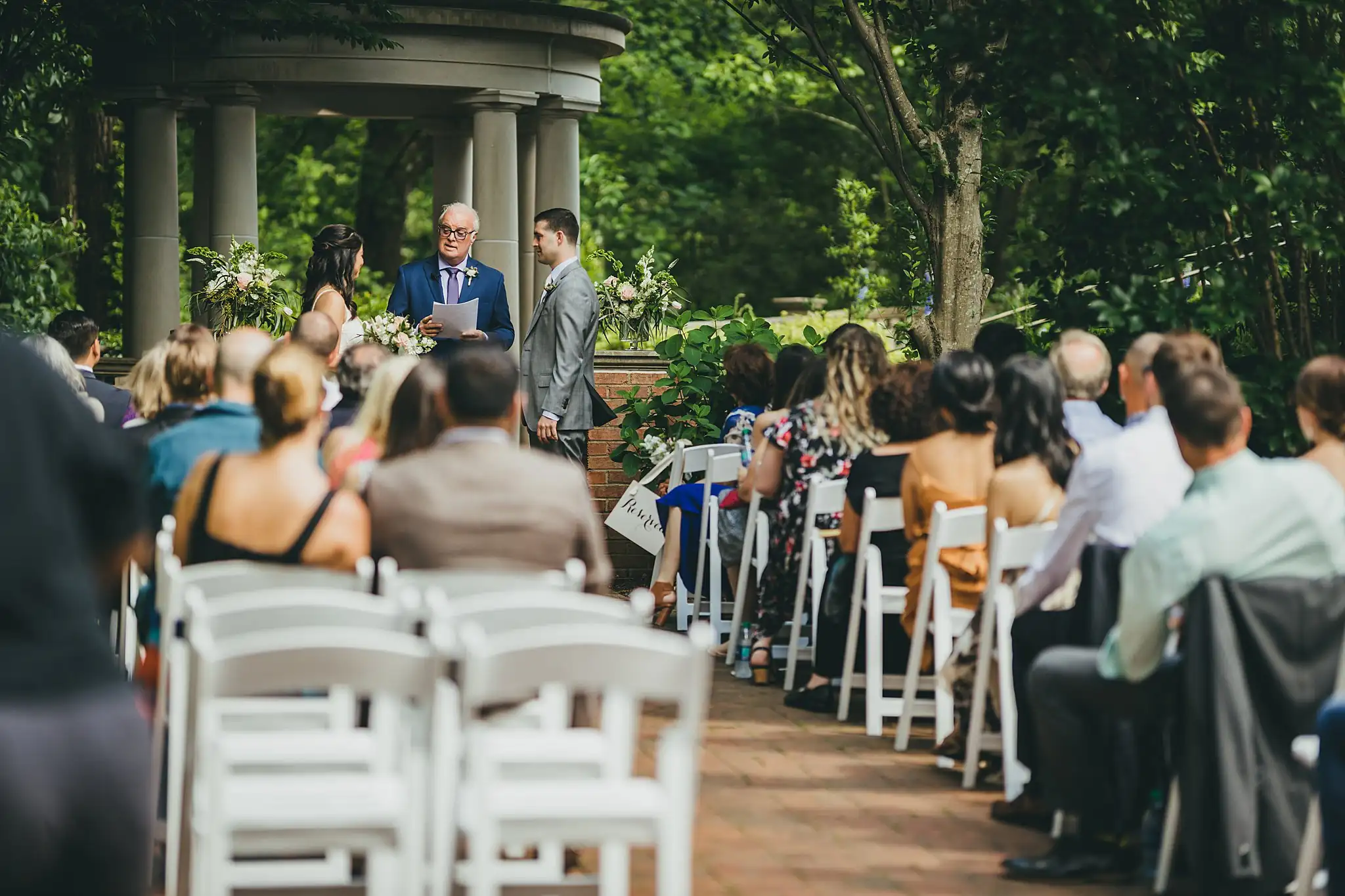Wedding Ceremony: the ceremony from behind the seated guests, at their wedding at the Atlanta Botanical Garden in Atlanta, GA