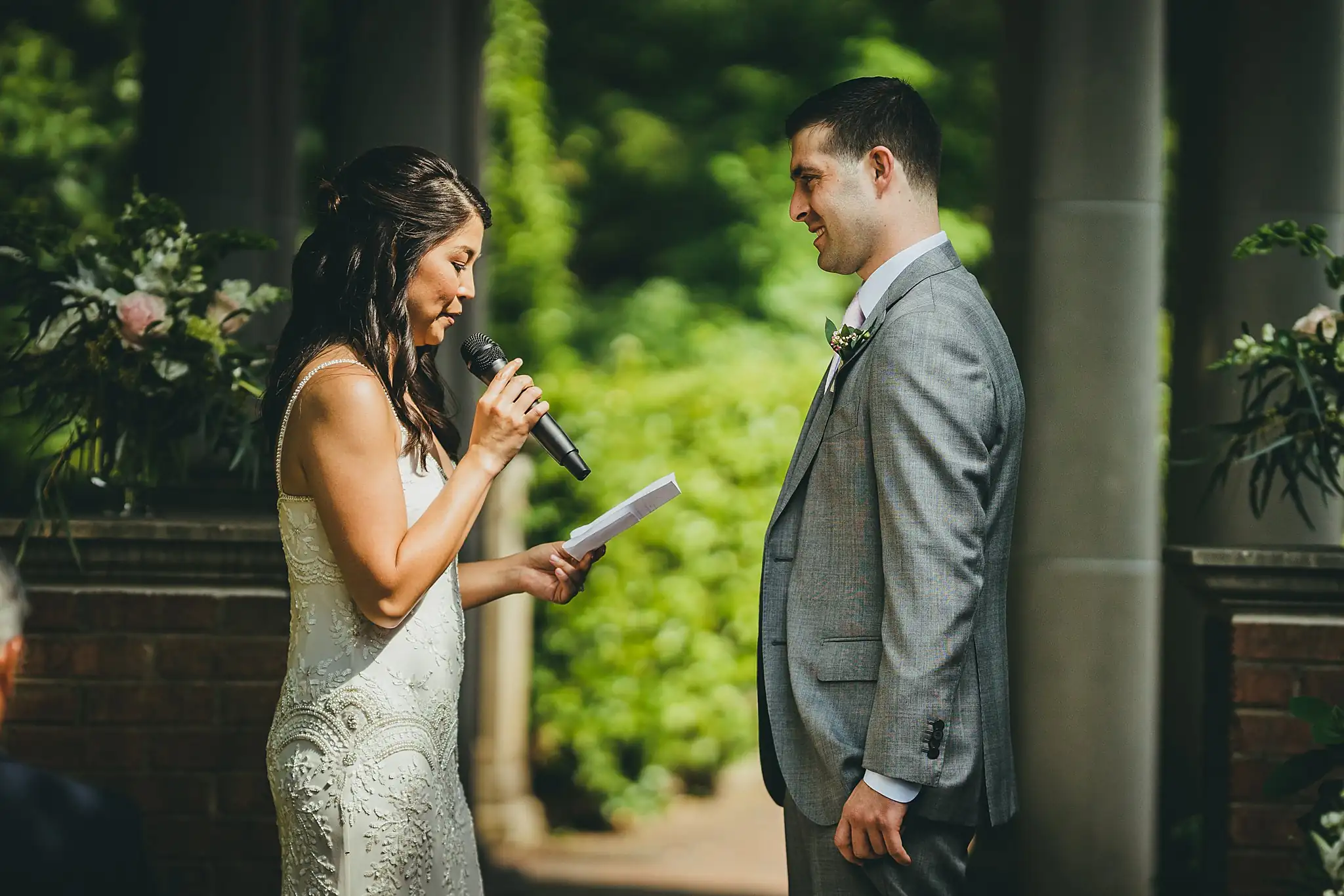 Wedding Ceremony: the bride reading her vows into a microphone, at their wedding at the Atlanta Botanical Garden in Atlanta, GA