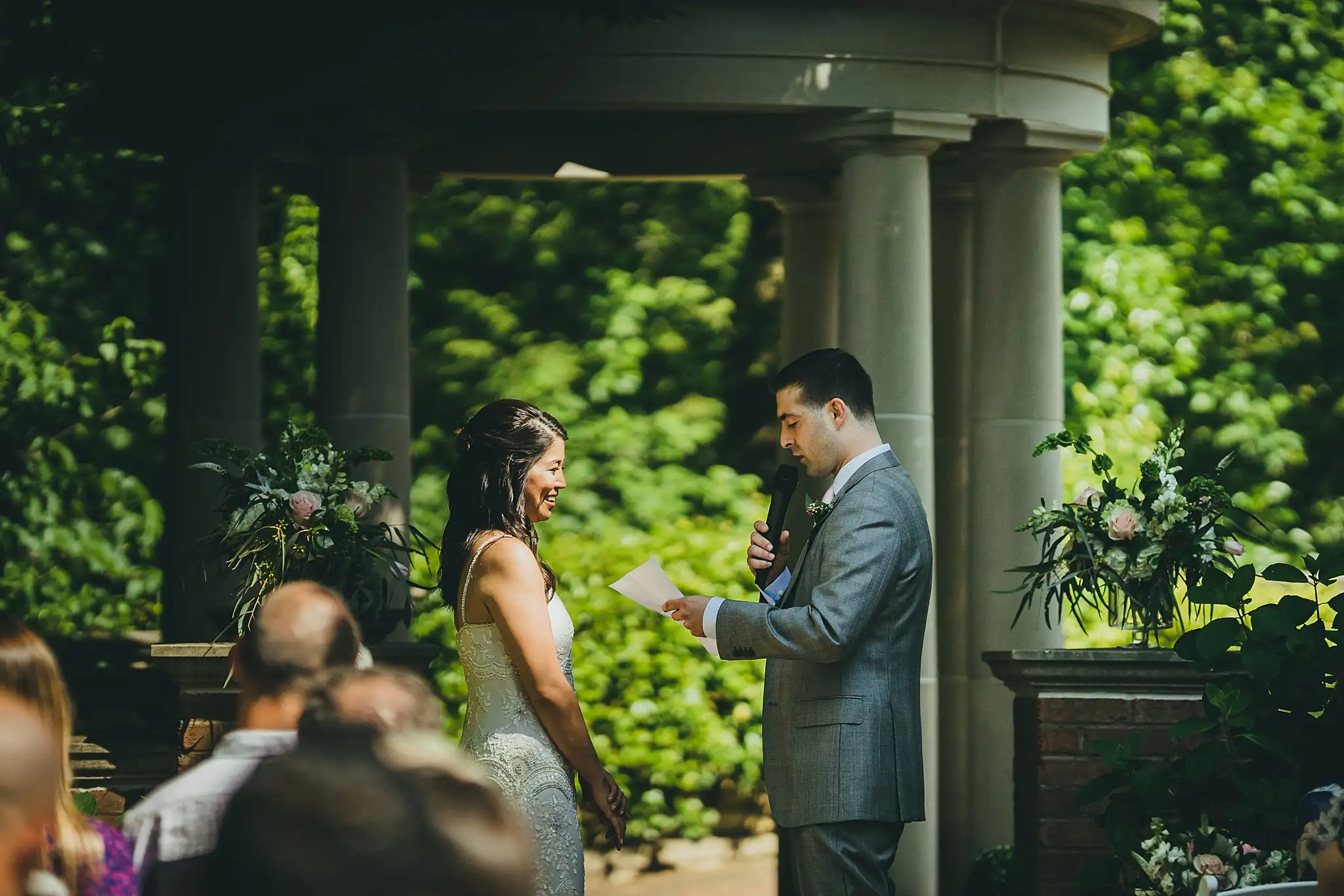Wedding Ceremony: the couple facing each other among the columns, at their wedding at the Atlanta Botanical Garden in Atlanta, GA