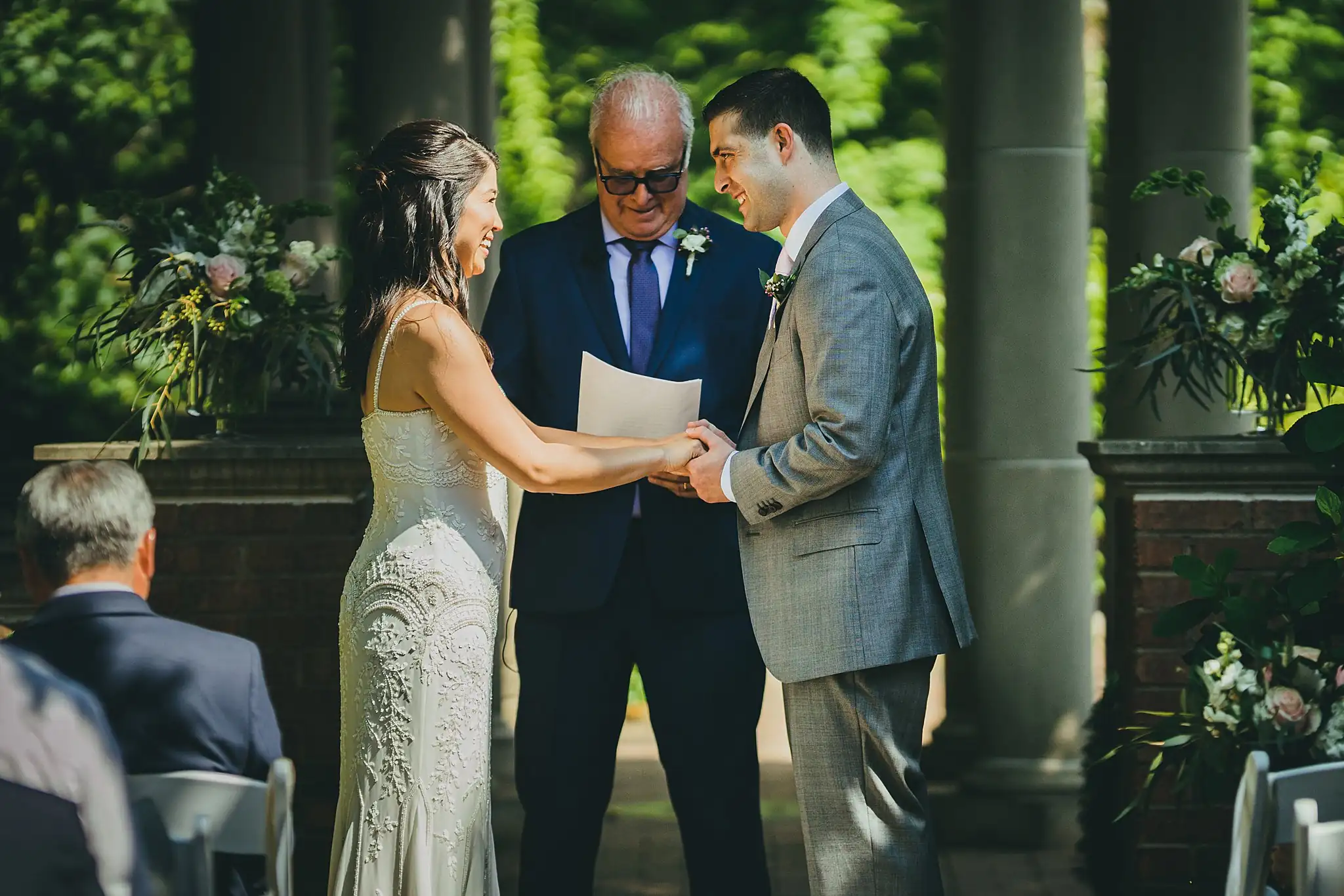 Wedding Ceremony: the ring exchange with the officiant, at their wedding at the Atlanta Botanical Garden in Atlanta, GA