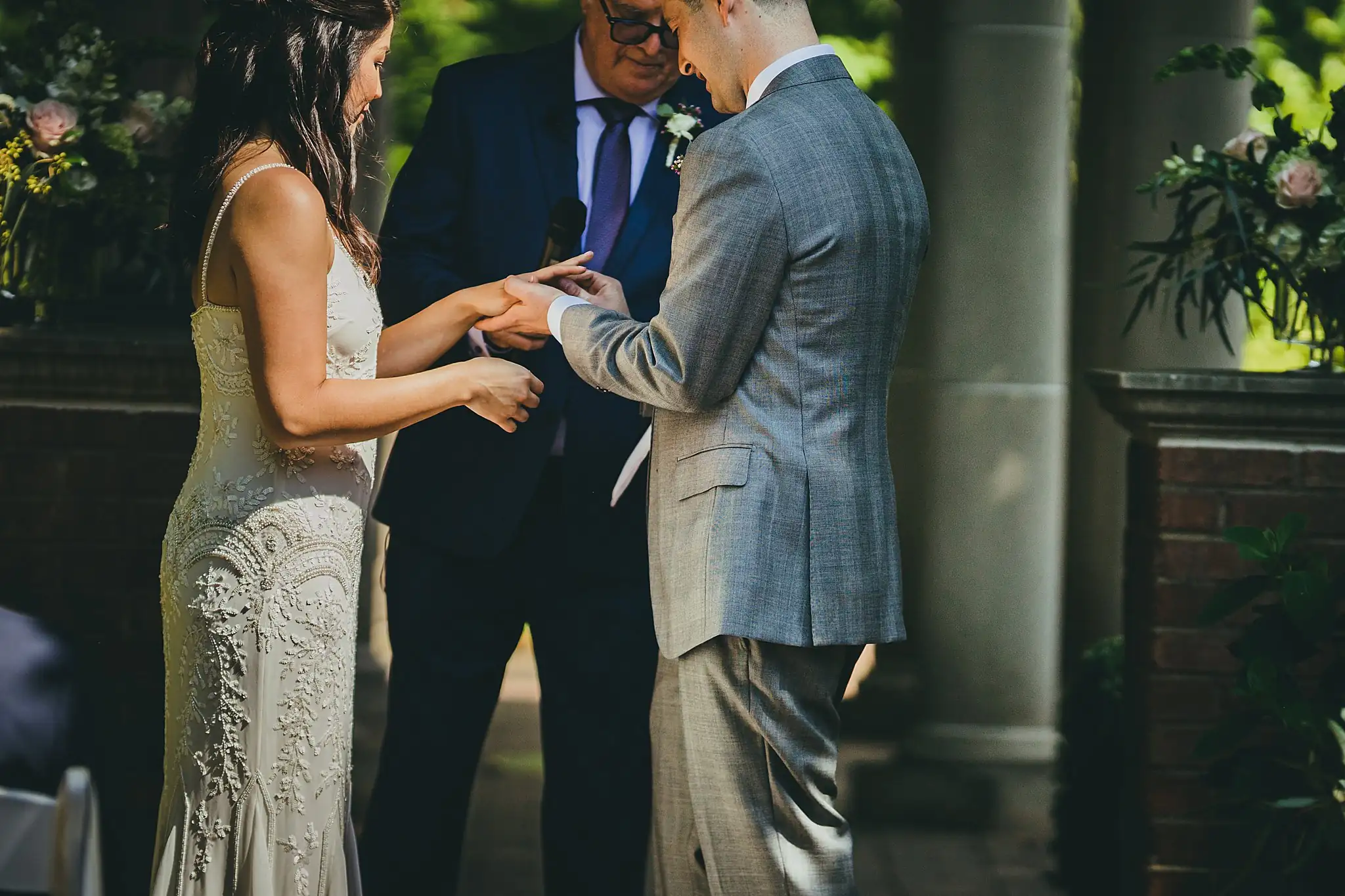 Wedding Ceremony: the ring being slid onto her finger, at their wedding at the Atlanta Botanical Garden in Atlanta, GA