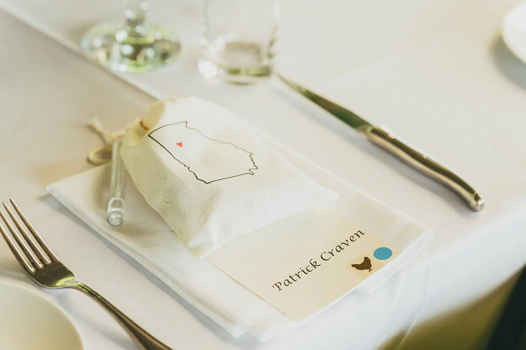 Reception Details: a place setting with a favour pouch and card, at their wedding at the Atlanta Botanical Garden in Atlanta, GA
