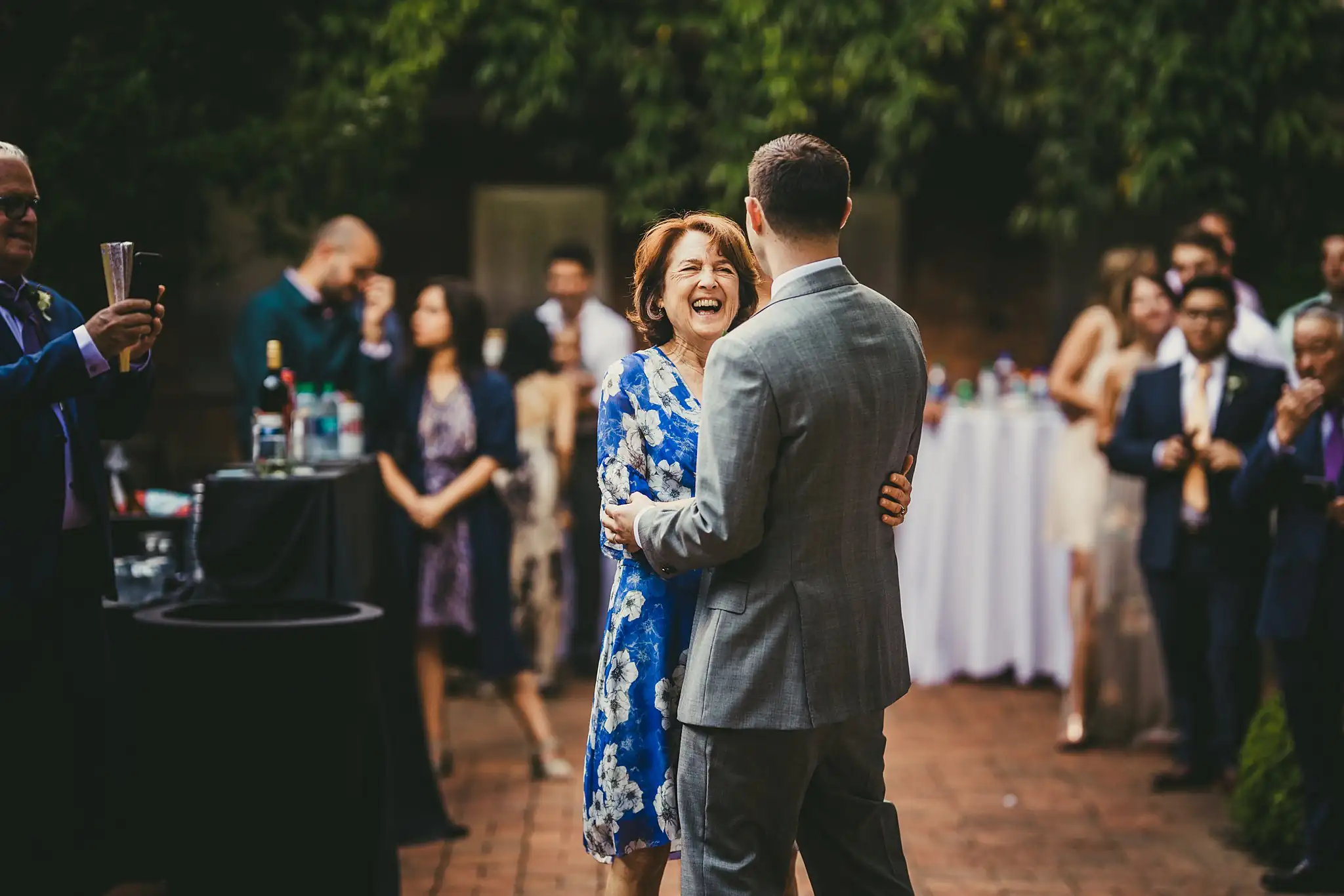 Parent Dance: the groom and his mother, guests around them, at their wedding at the Atlanta Botanical Garden in Atlanta, GA