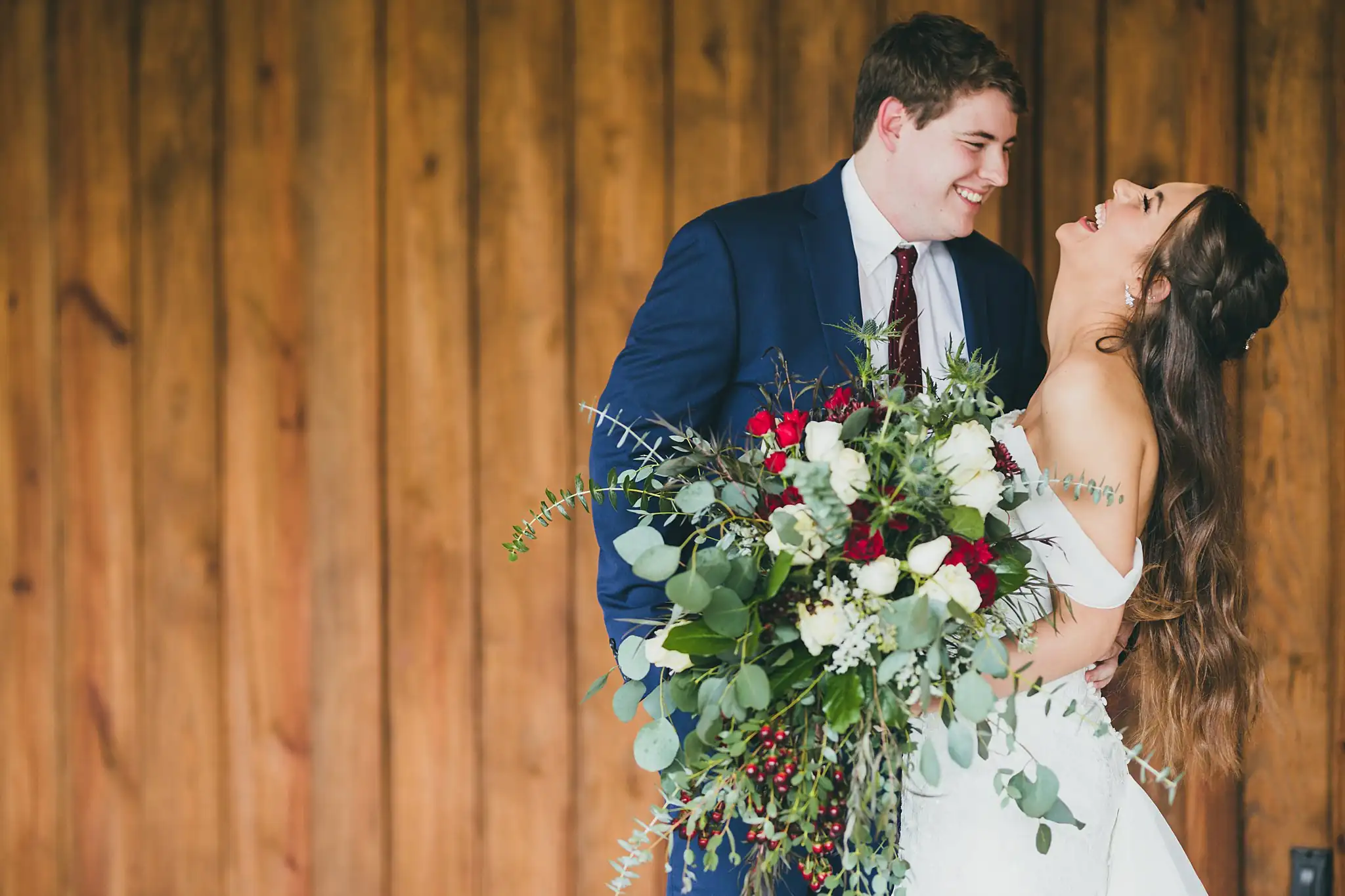 Barn at Harper Pines Wedding Thomaston, GA Atlanta Wedding Photographers Wedding Formals: the bride laughing with her red and white bouquet, at their wedding at the Barn at Harper Pines in Thomaston, GA