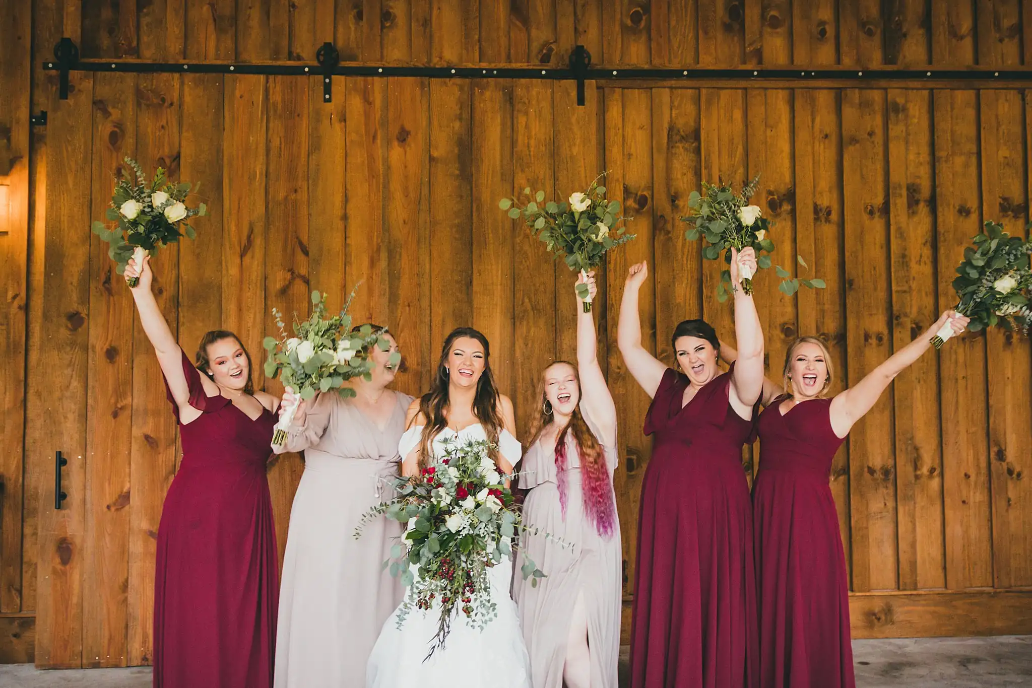 Barn at Harper Pines Wedding Thomaston, GA Atlanta Wedding Photographers Wedding Party: the bridesmaids cheering with their bouquets raised, at their wedding at the Barn at Harper Pines in Thomaston, GA