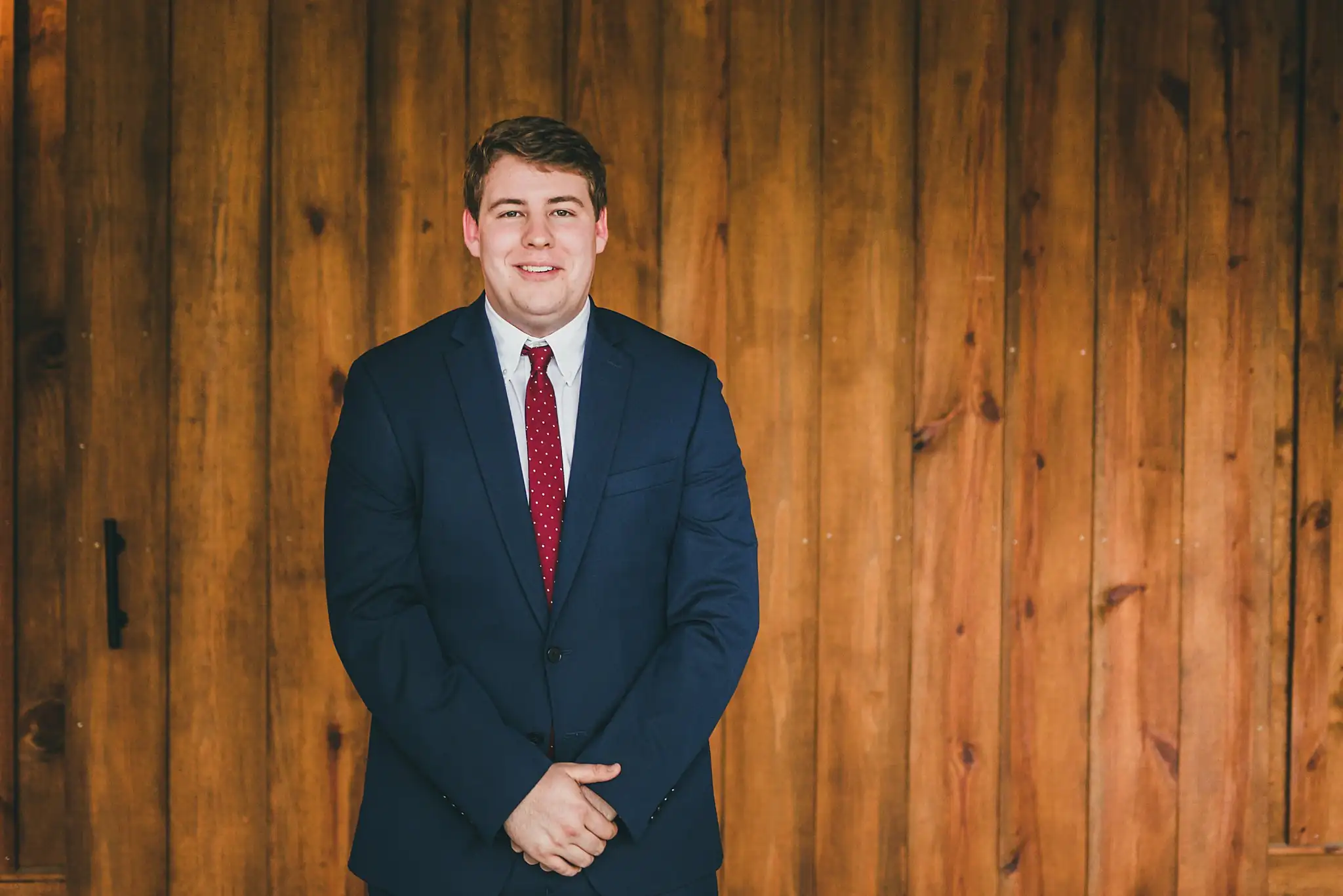 Barn at Harper Pines Wedding Thomaston, GA Atlanta Wedding Photographers Wedding Formals: the groom in his navy suit against the barn wall, at their wedding at the Barn at Harper Pines in Thomaston, GA