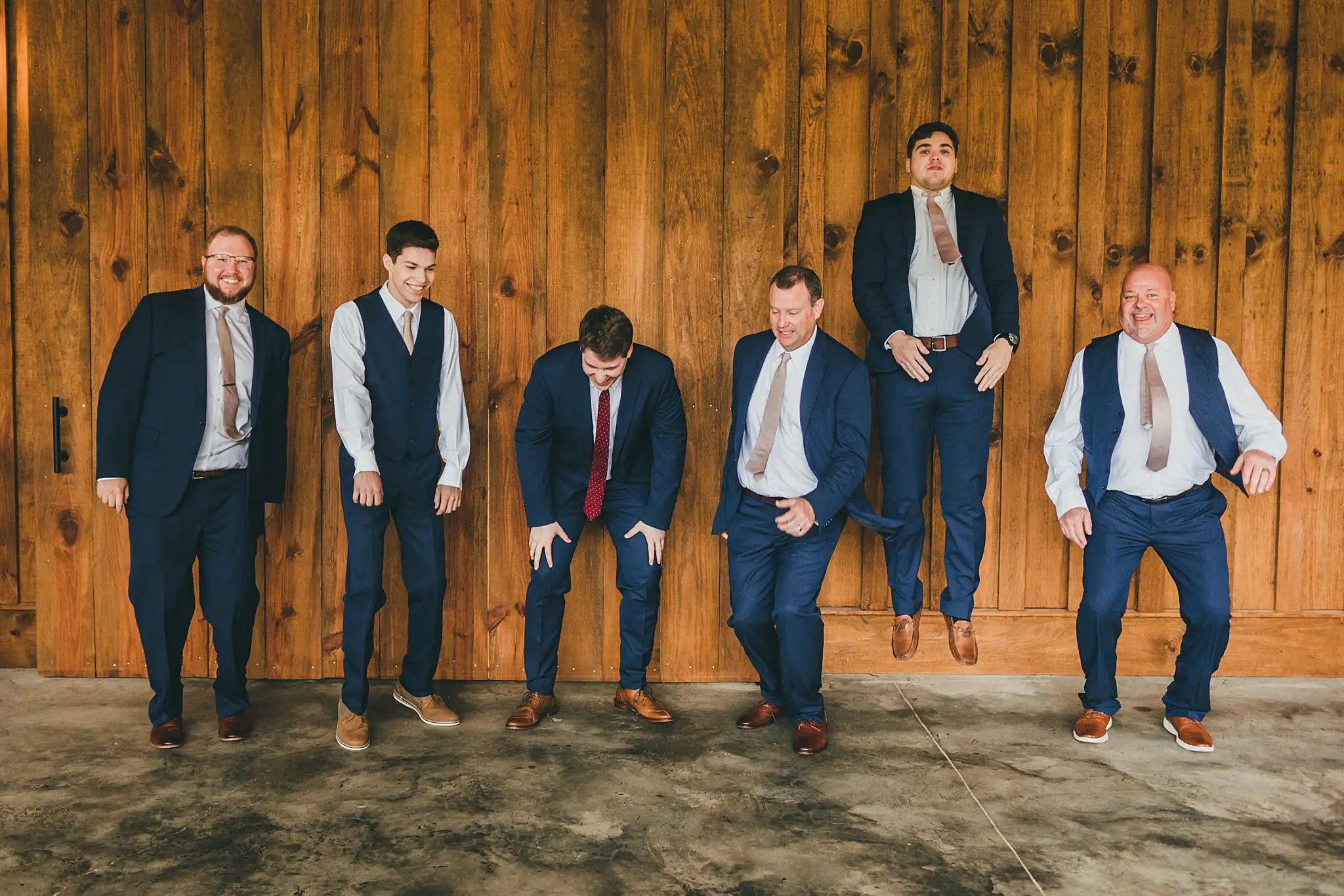 Barn at Harper Pines Wedding Thomaston, GA Atlanta Wedding Photographers Wedding Party: the groomsmen jumping against the barn wall, at their wedding at the Barn at Harper Pines in Thomaston, GA