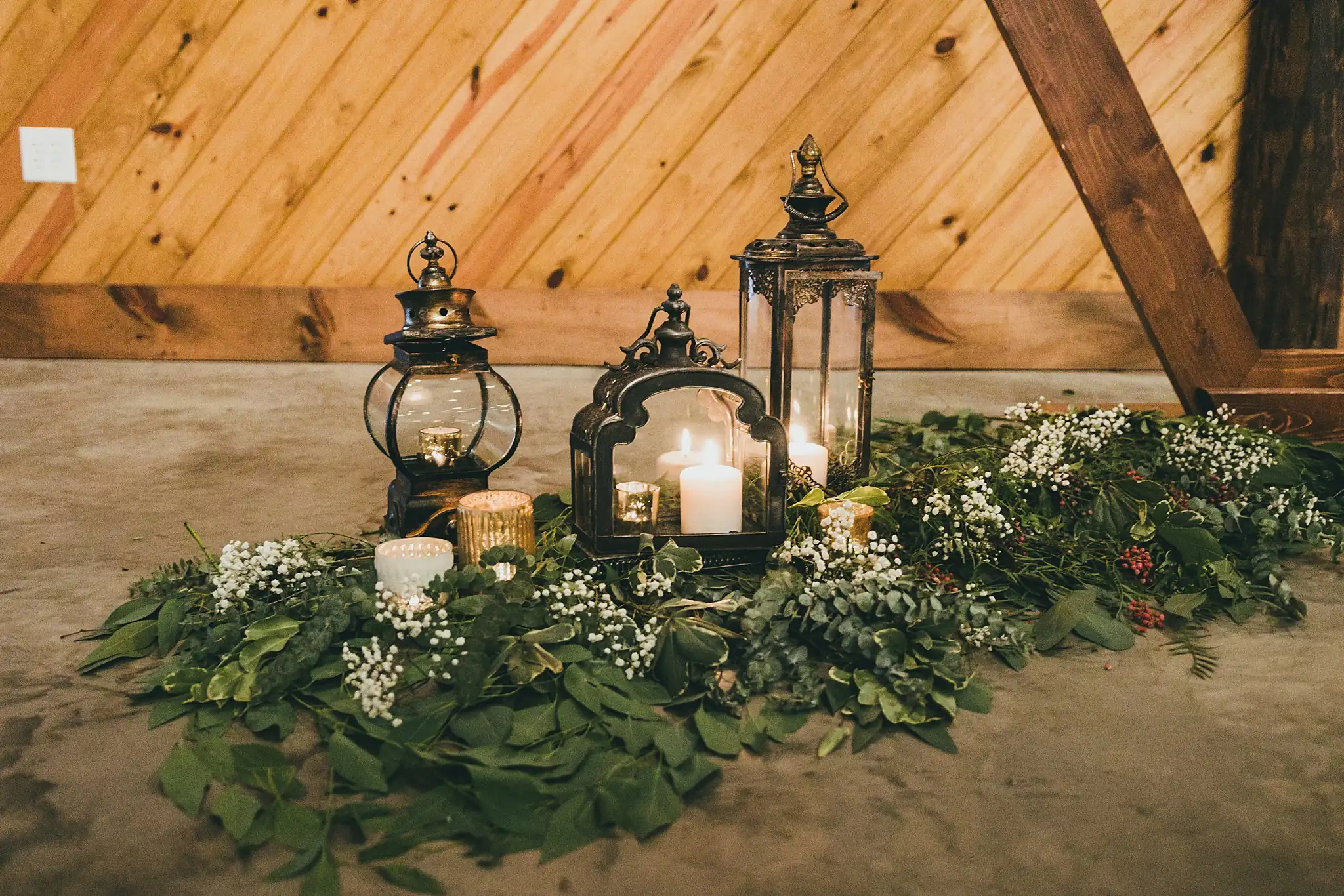Barn at Harper Pines Wedding Thomaston, GA Atlanta Wedding Photographers Wedding Details: candles and lanterns set in greenery at the altar, at a wedding at the Barn at Harper Pines in Thomaston, GA