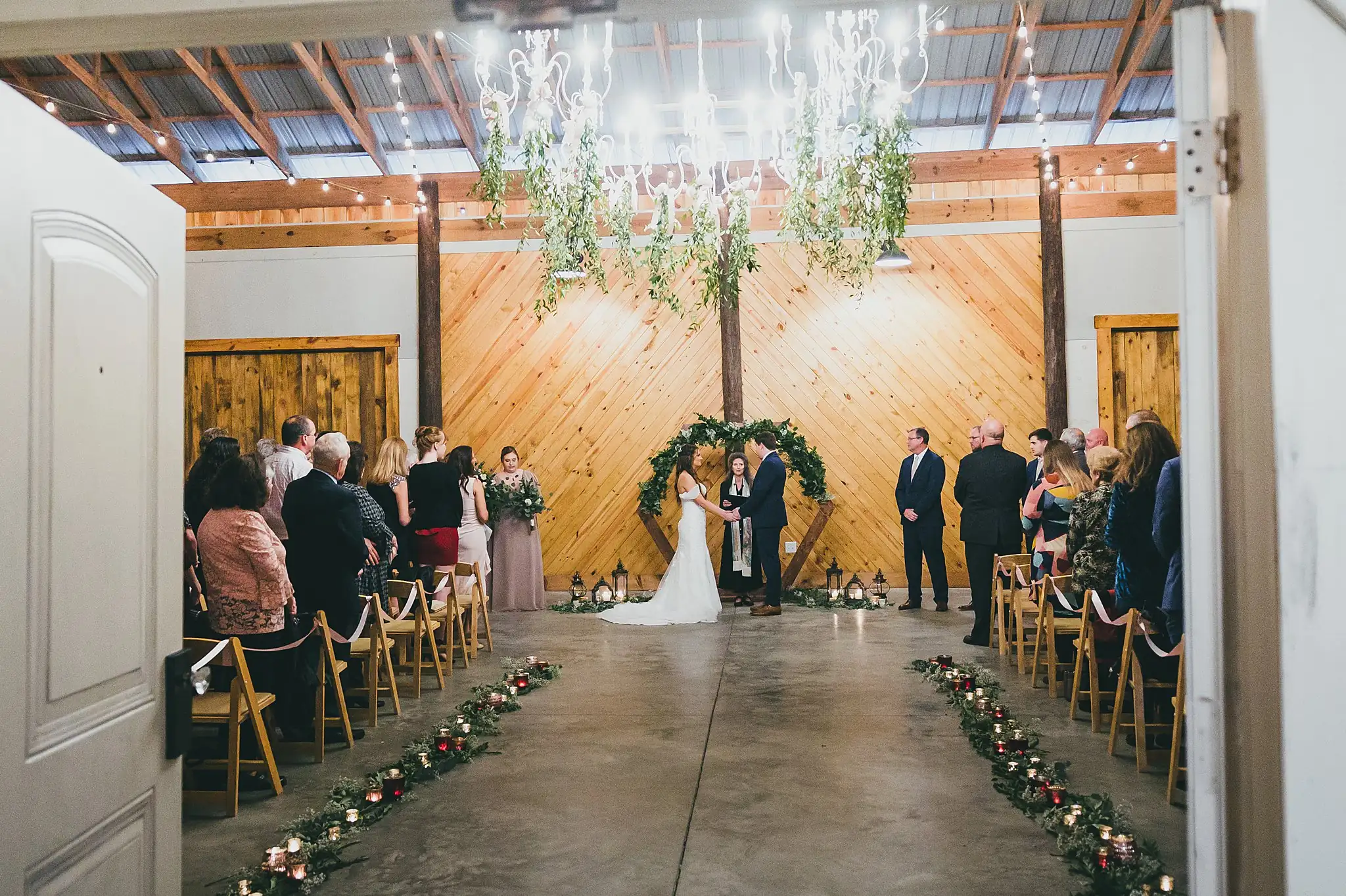 Barn at Harper Pines Wedding Thomaston, GA Atlanta Wedding Photographers Wedding Ceremony: the couple at the arch seen down the aisle, at their wedding at the Barn at Harper Pines in Thomaston, GA
