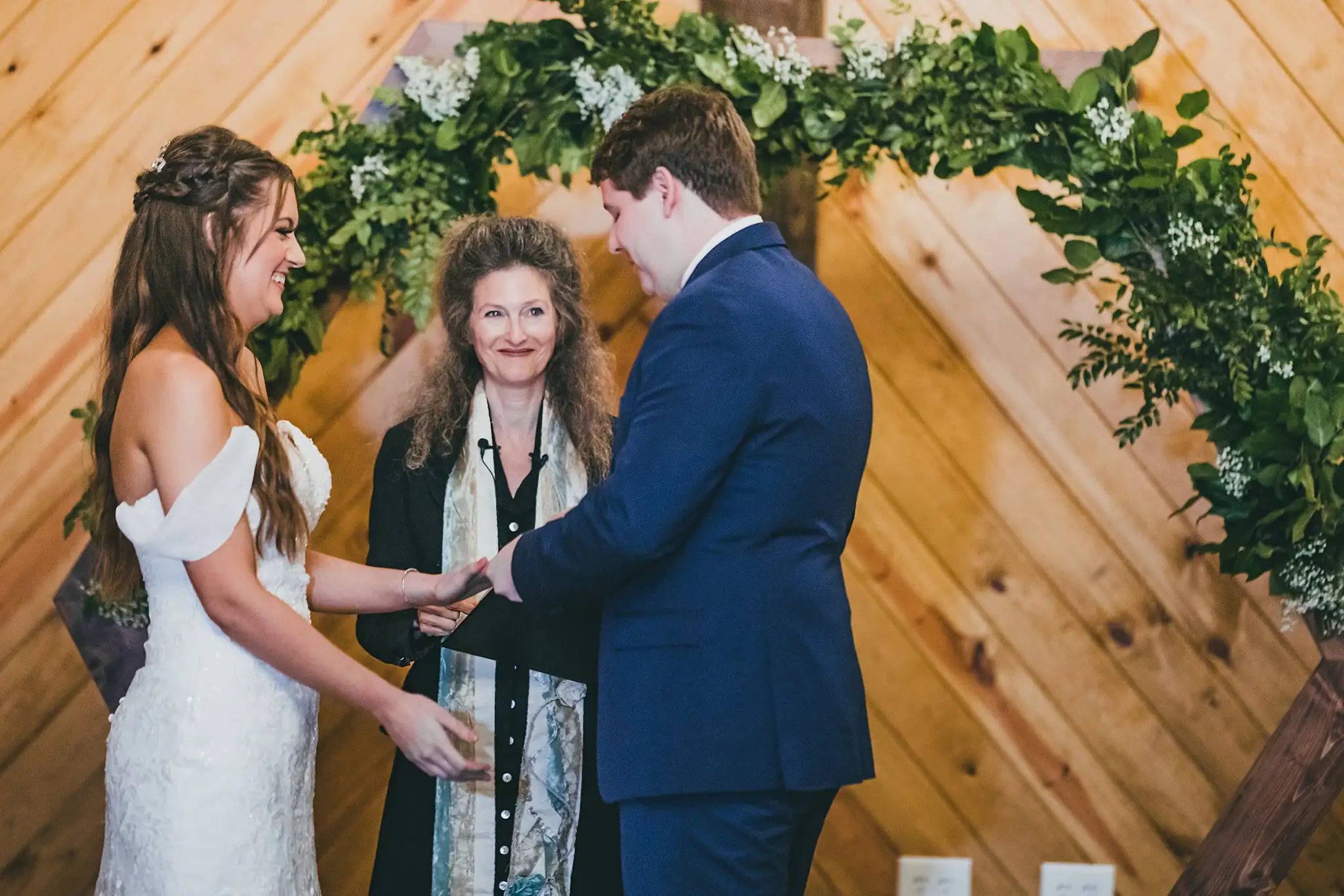 Barn at Harper Pines Wedding Thomaston, GA Atlanta Wedding Photographers Wedding Ceremony: the ring exchange beneath the greenery arch, at their wedding at the Barn at Harper Pines in Thomaston, GA