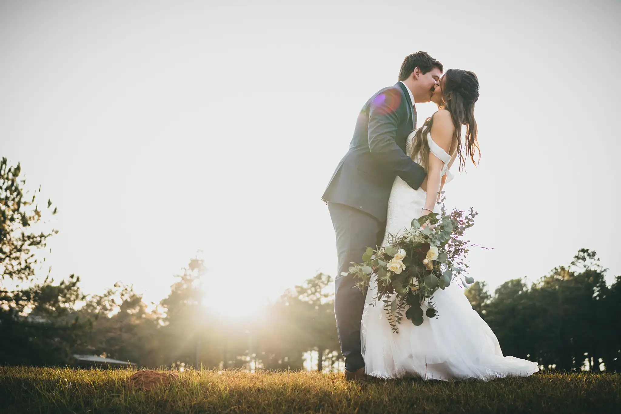 Barn at Harper Pines Wedding Thomaston, GA Atlanta Wedding Photographers Wedding Formals: the groom dipping the bride at sunset, at their wedding at the Barn at Harper Pines in Thomaston, GA