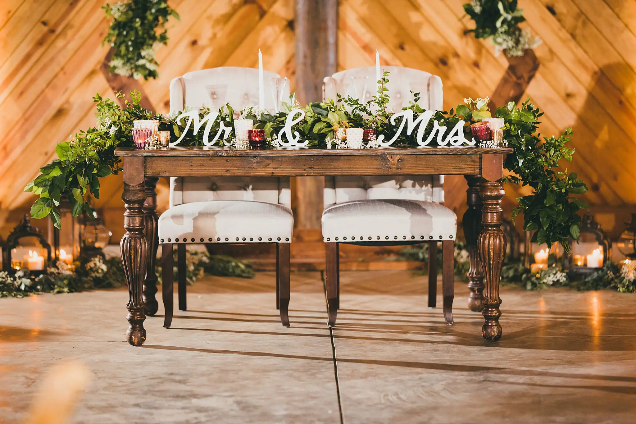 Barn at Harper Pines Wedding Thomaston, GA Atlanta Wedding Photographers Reception Details: the sweetheart table set with greenery and candles, at a wedding at the Barn at Harper Pines in Thomaston, GA